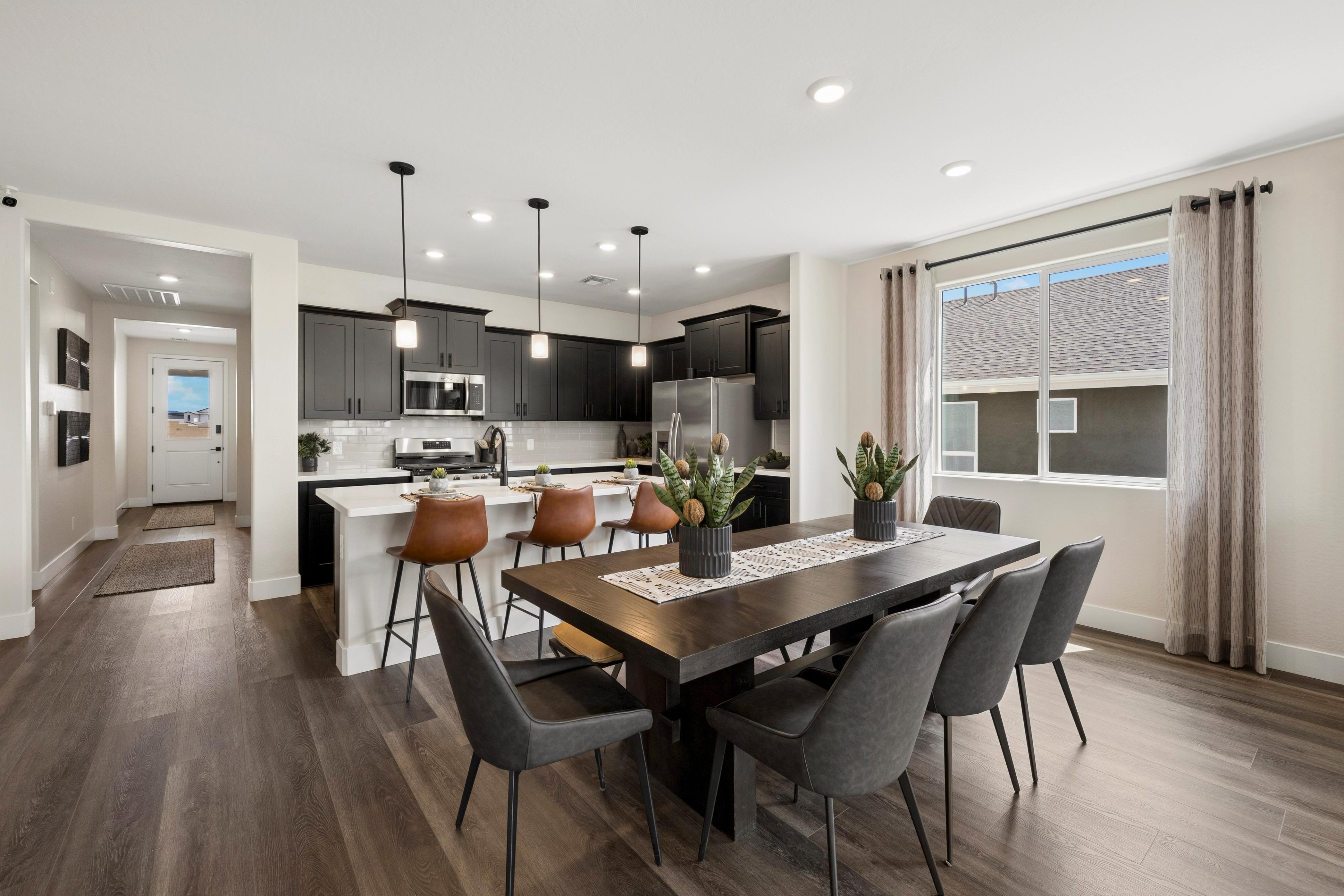 Open-concept kitchen dining area at South Ranch Western Collection in Prescott AZ with dark cabinets, wood island, upholstered stools, and hardwood floors