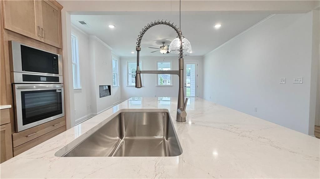 Modern kitchen island with quartz countertops and stainless sink in The Glenwood A floor plan at Wehunt Meadows, Hoschton.