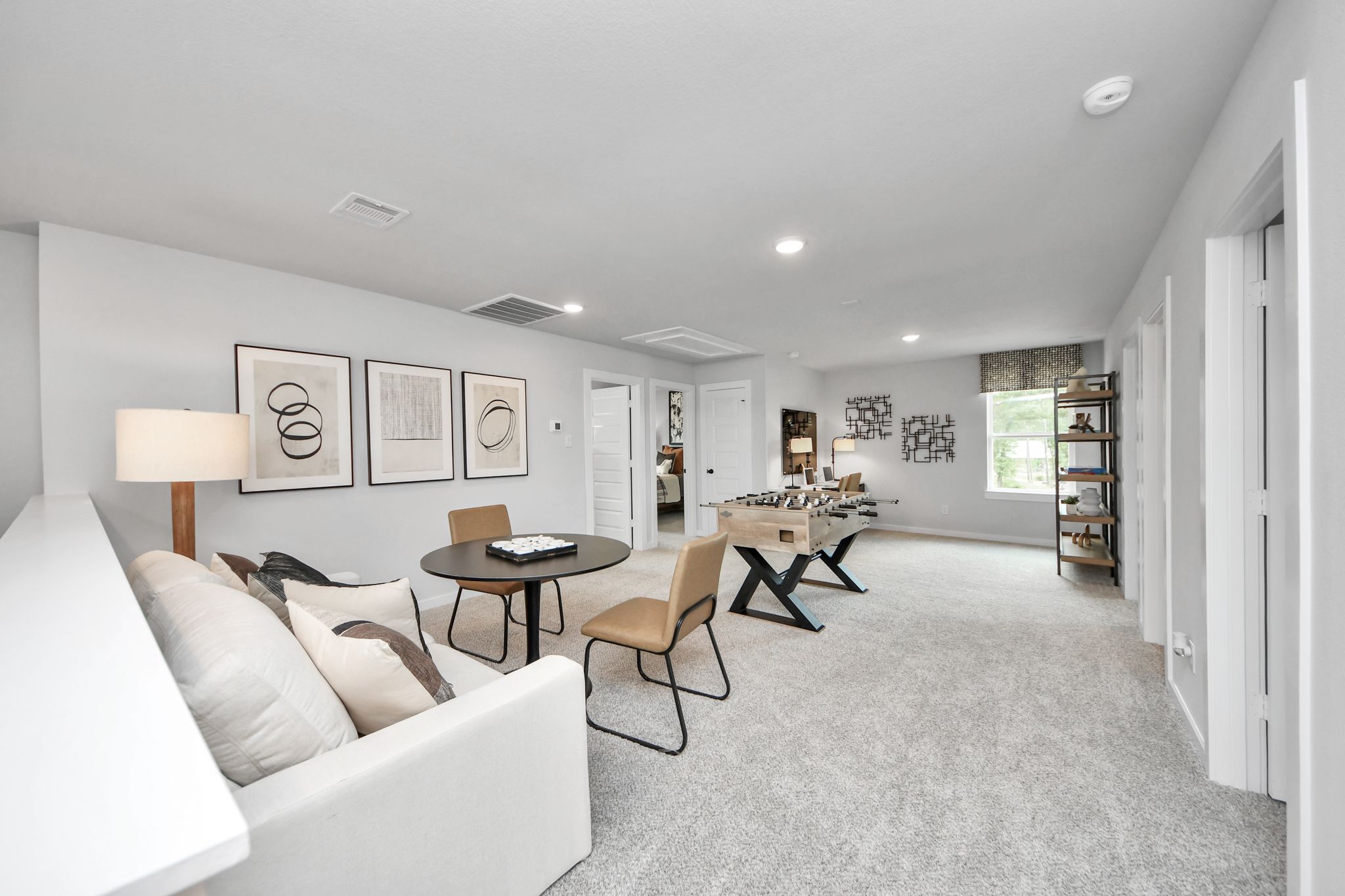 Spacious game room at Robins Landing in Houston, TX by Davidson Homes featuring a foosball table, lounge area, and desk.