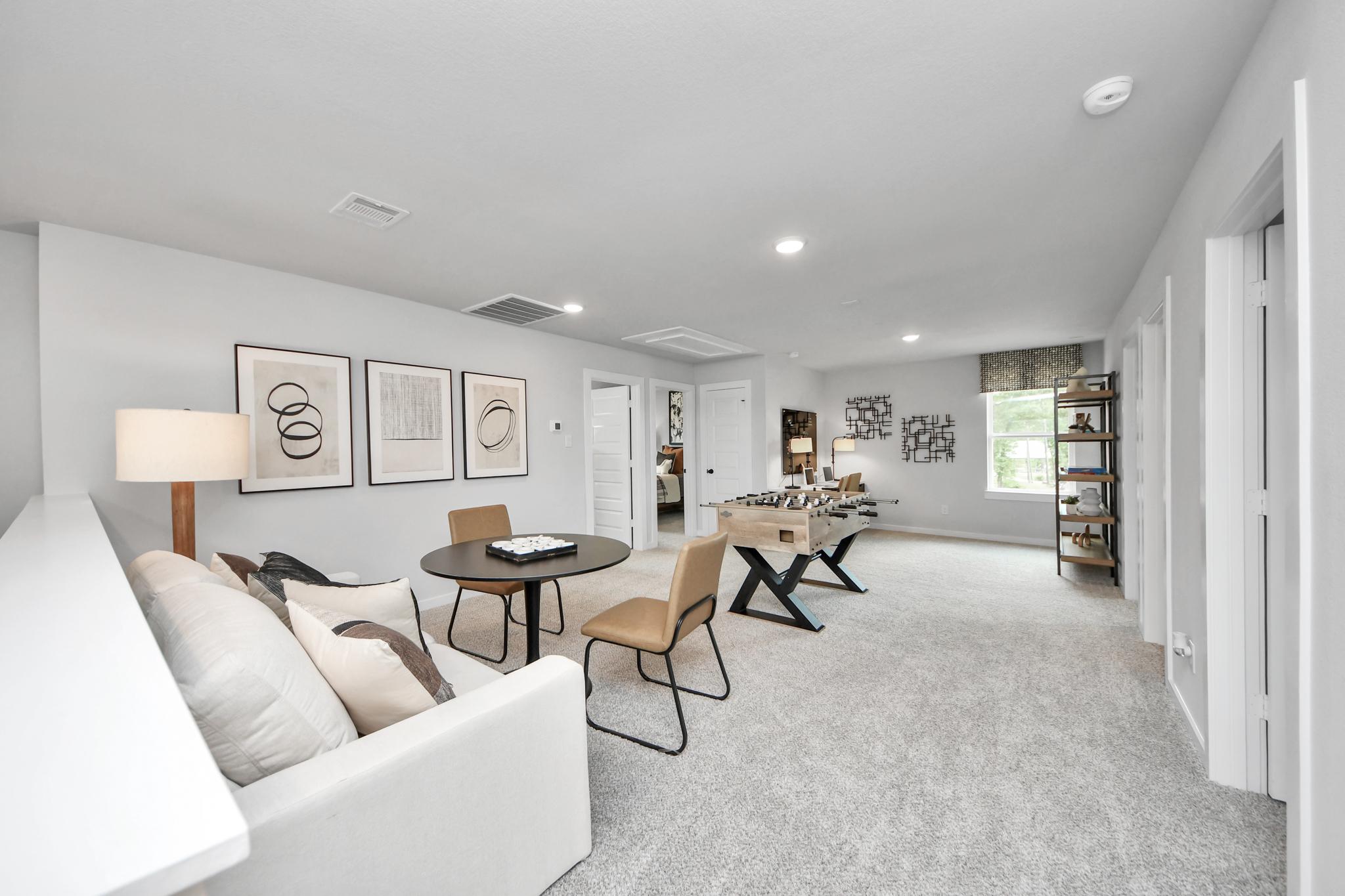 Spacious game room at Robins Landing in Houston, TX by Davidson Homes featuring a foosball table, lounge area, and desk.