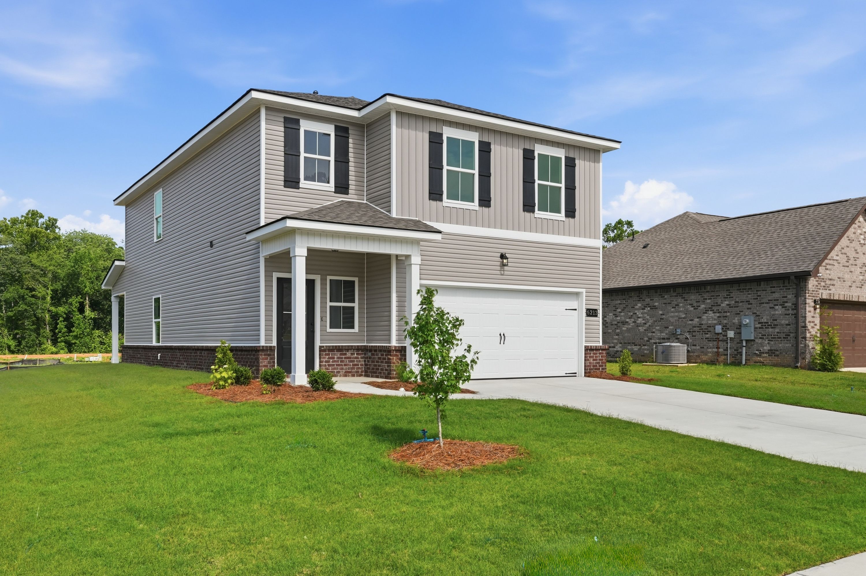 Two-story exterior of The Russell A by Davidson Homes featuring a gray siding facade and two-car garage in New Market, AL.