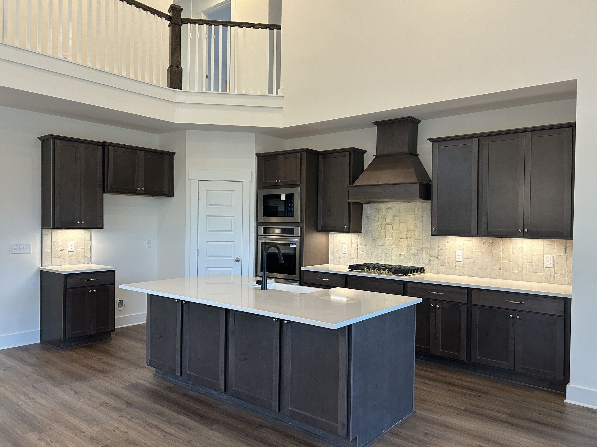 Modern kitchen with dark shaker cabinets, white quartz island, gas range, and open two-story loft in Davidson Homes Ridgeport F, Mt. Juliet, TN