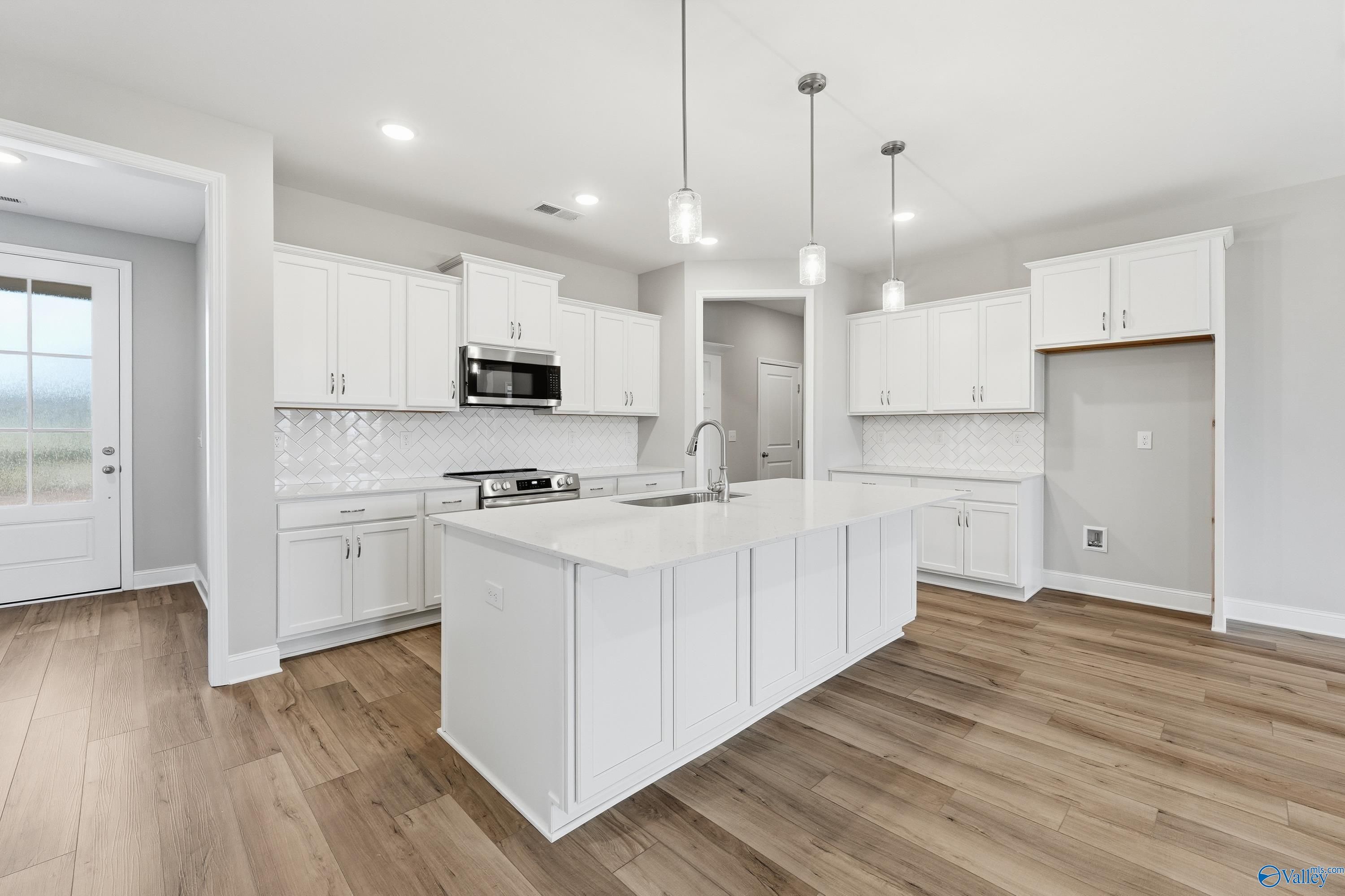 Modern white kitchen with quartz island, stainless appliances, subway backsplash in Davidson Homes The Lanier, Meridianville, Alabama