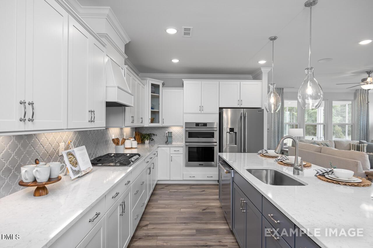 Modern gourmet kitchen with white cabinets, quartz countertops, and stainless appliances in The Magnolia II B, Apex, NC.