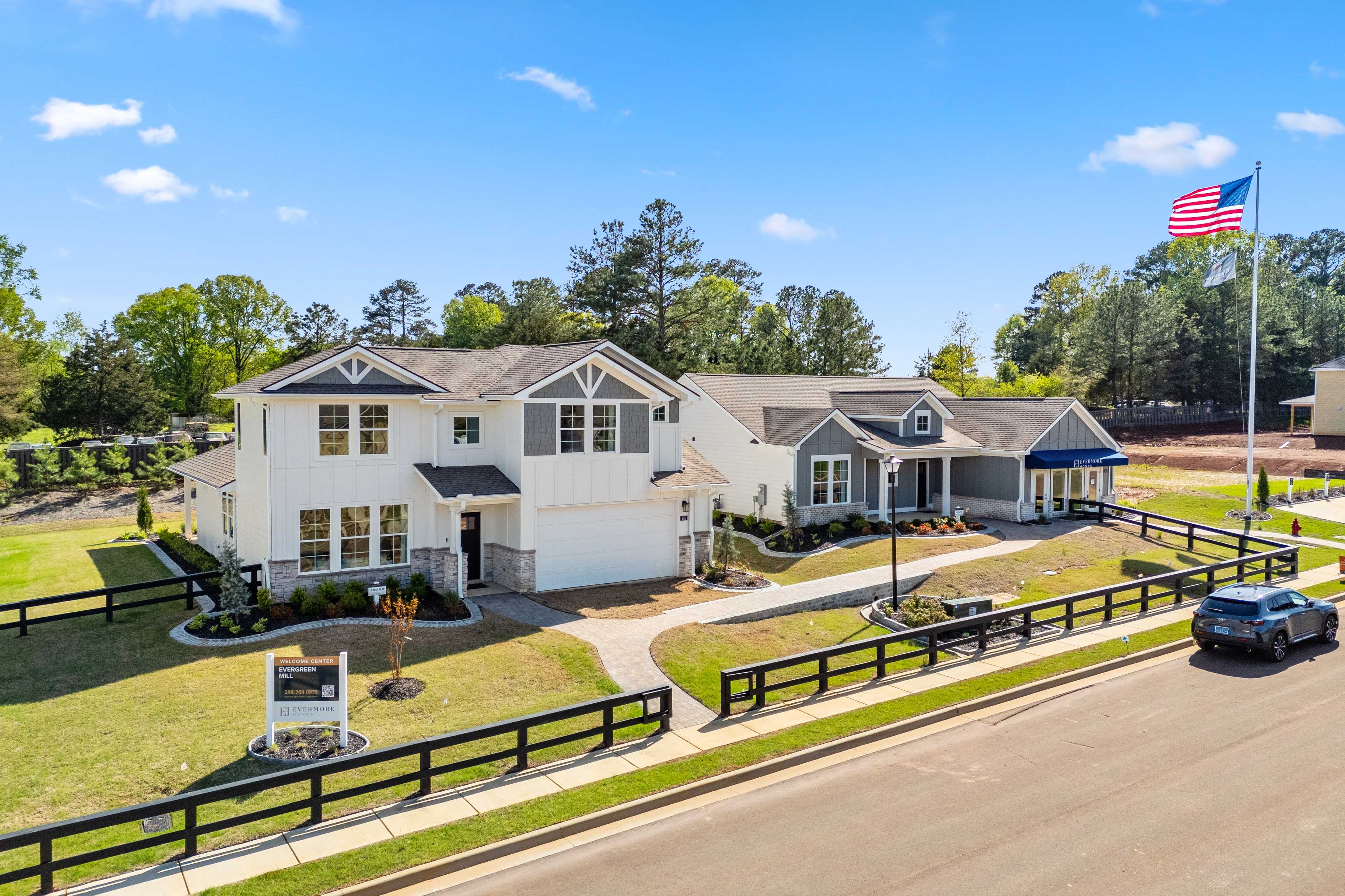 Modern homes at Evergreen Mill in Madison, Alabama with white siding, gabled roofs, American flag, black fence and lush green lawns