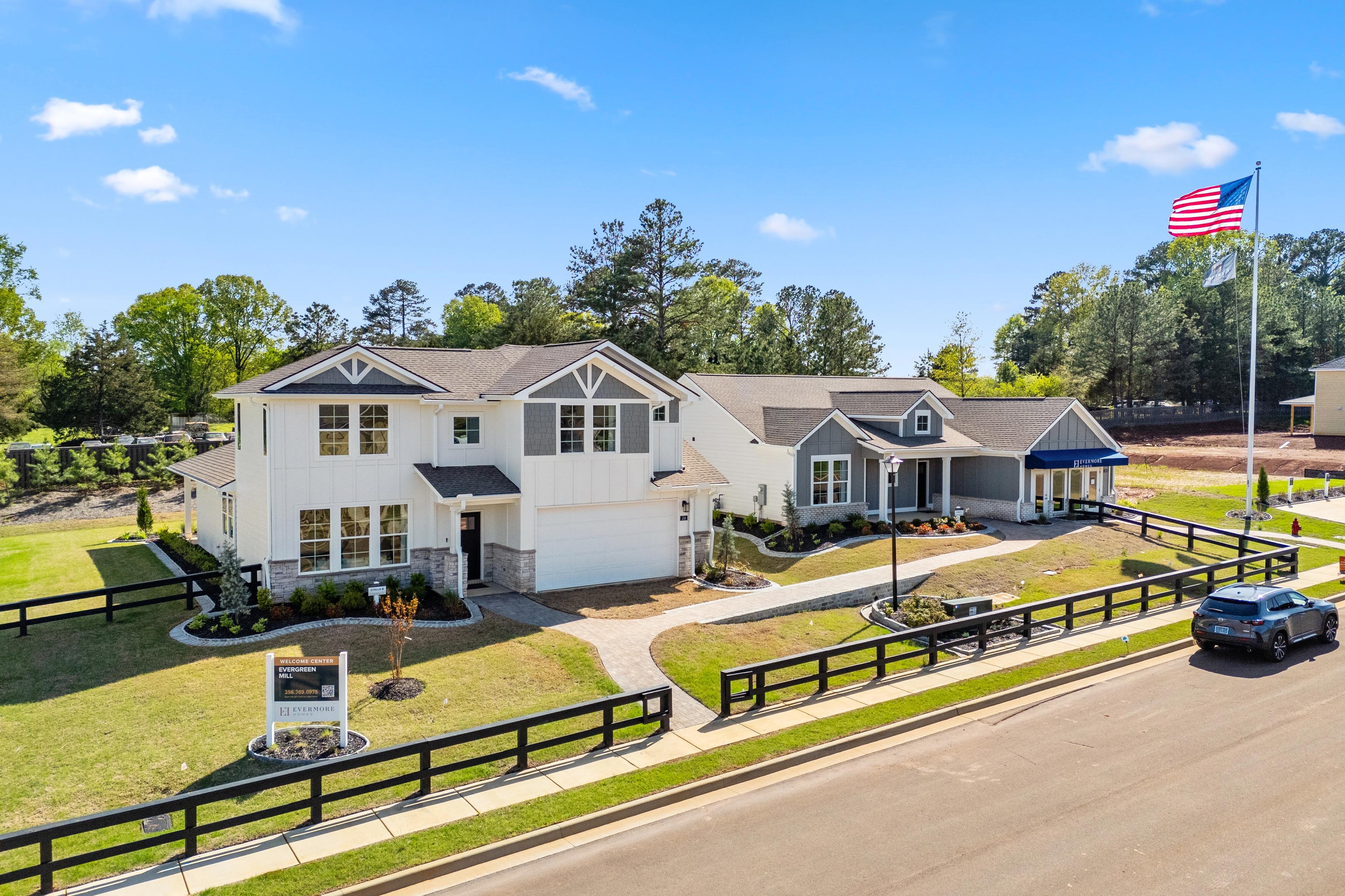 Modern homes at Evergreen Mill in Madison, Alabama with white siding, gabled roofs, American flag, black fence and lush green lawns