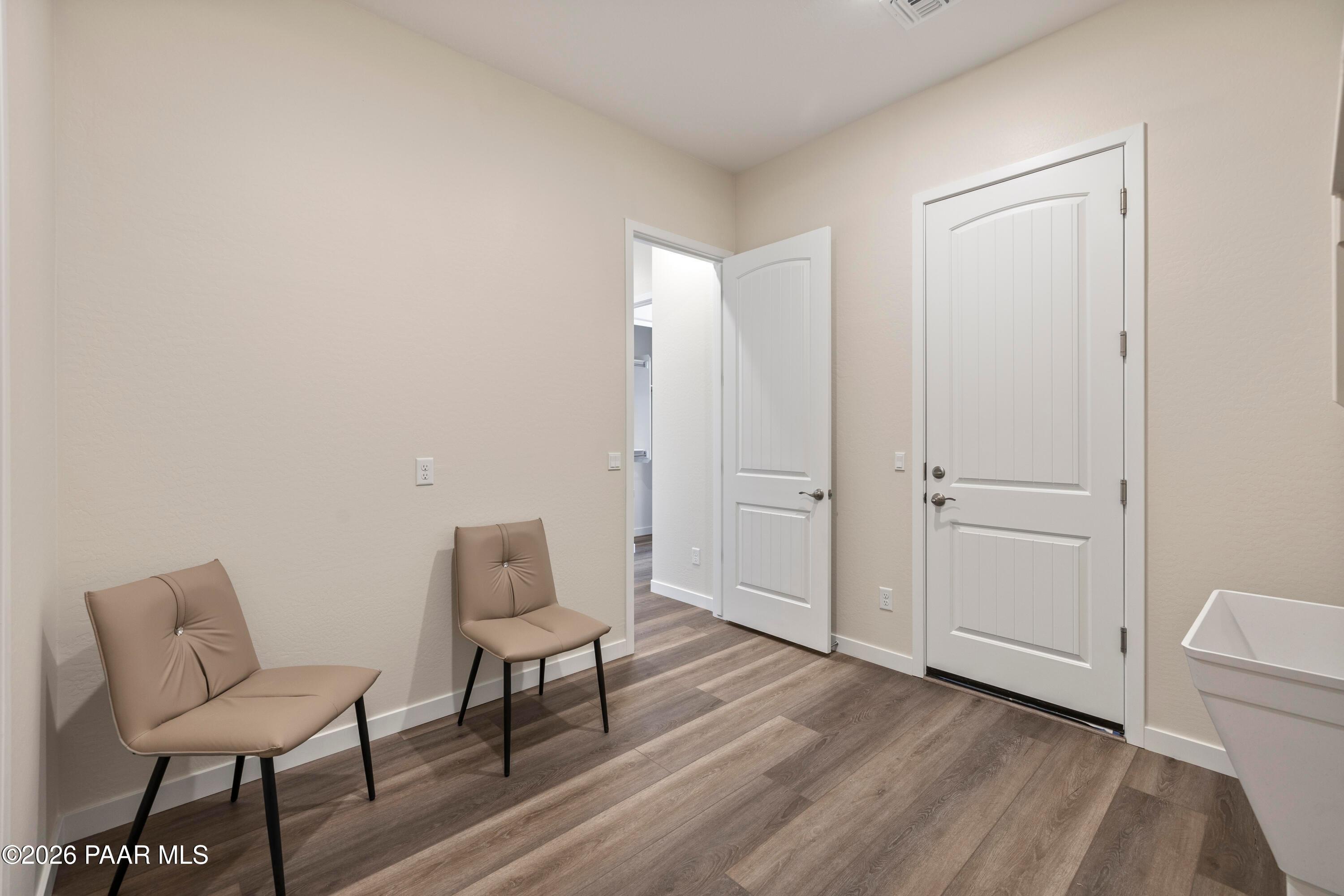 Laundry room with tufted beige chairs, deep white utility sink, luxury vinyl plank flooring in Davidson Homes The Soleil E, Prescott AZ