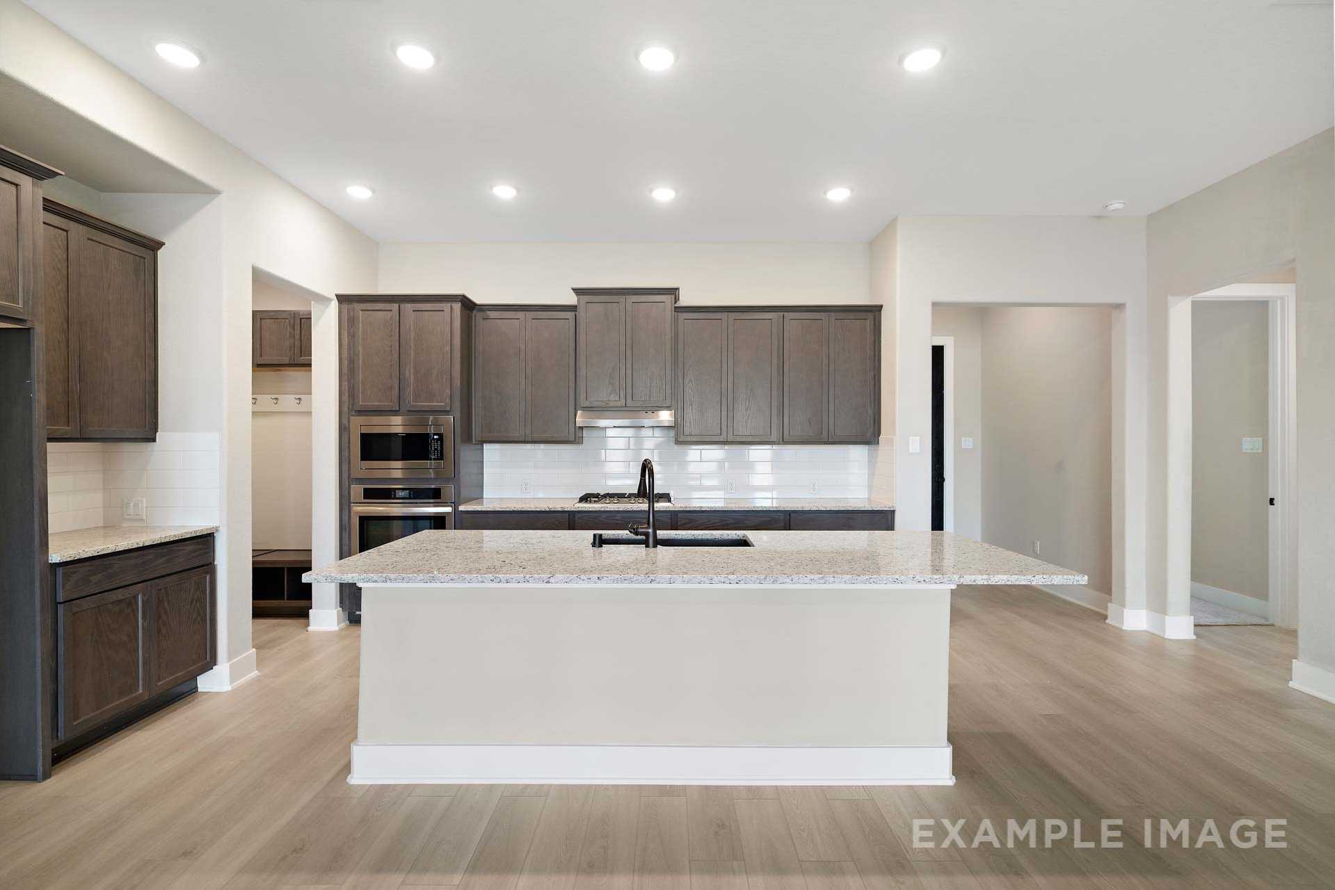 Spacious open-concept kitchen in The Elizabeth A by Davidson Homes with dark shaker cabinets, granite island, and stainless appliances