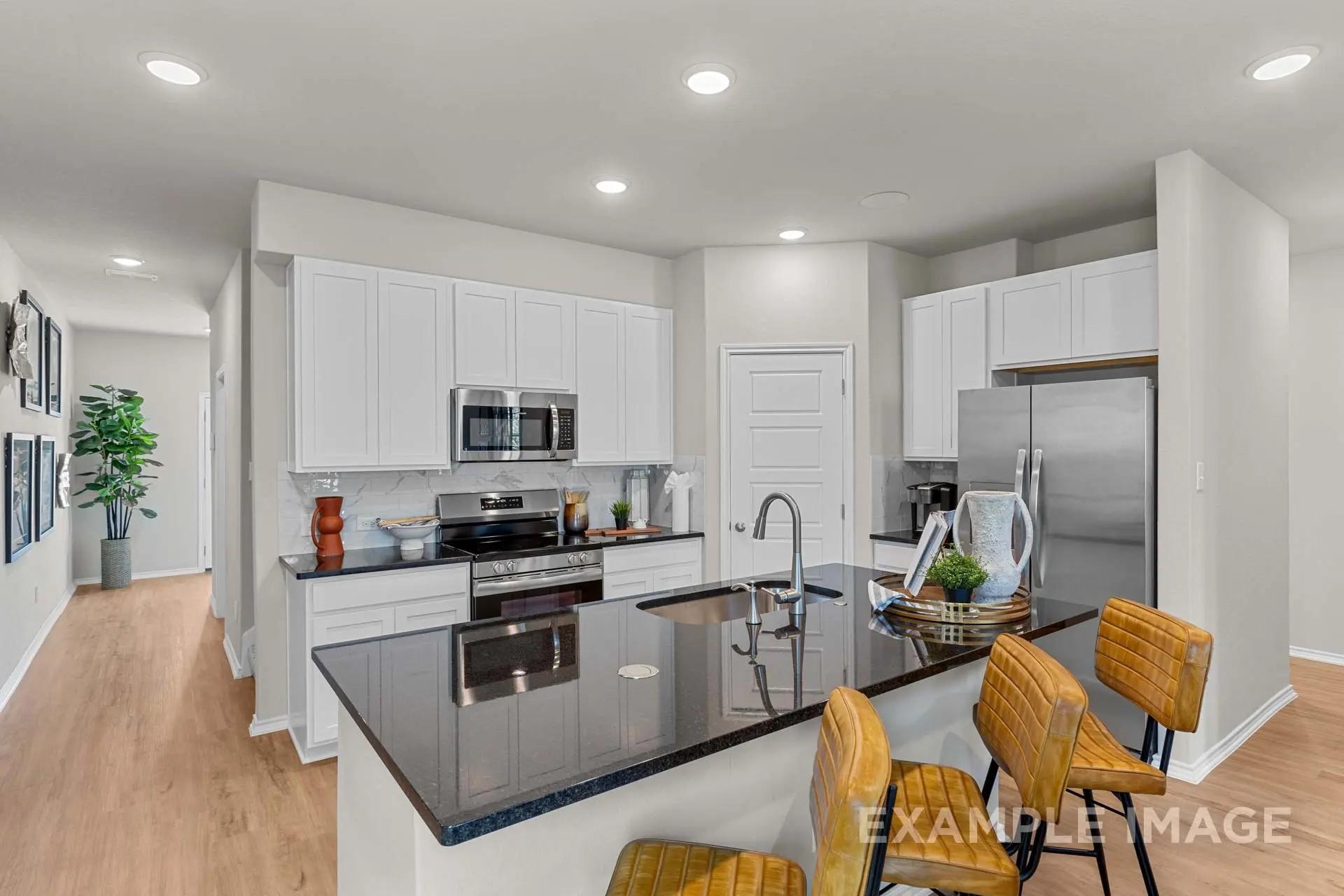 Modern kitchen with white cabinets, black granite island, and stainless appliances in Davidson Homes' The Sabine H floor plan.