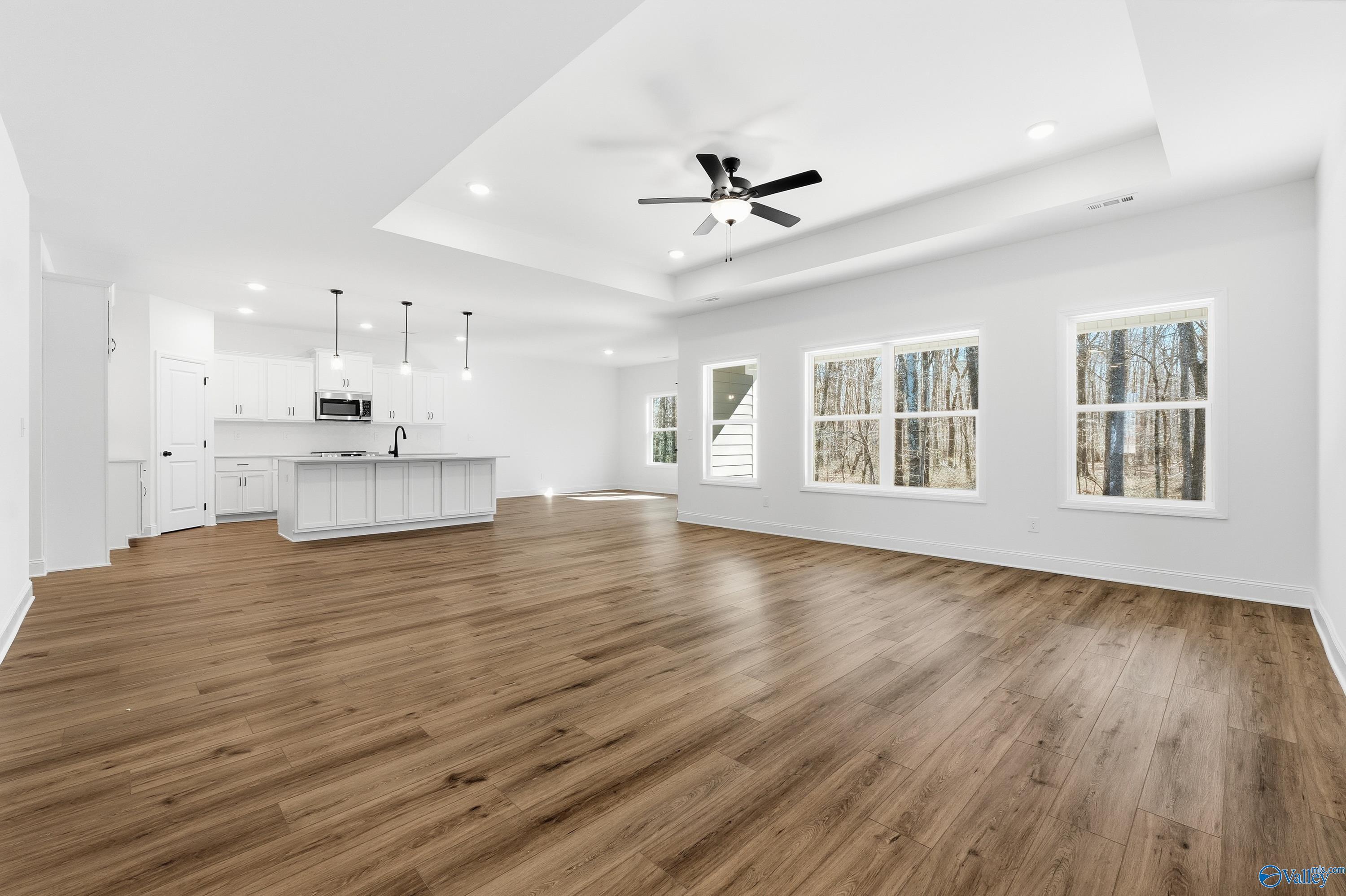 Open-concept kitchen featuring white cabinets, large island, pendant lights, and hardwood floors in Davidson Homes The Rockford D, Hazel Green, AL