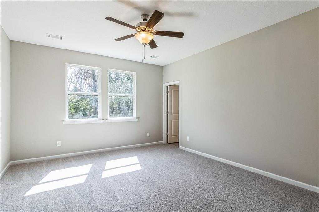 Bright secondary bedroom with ceiling fan, large sunny windows, and gray carpet in Evermore Homes The Stella, Ivy Glen, Perry, Georgia