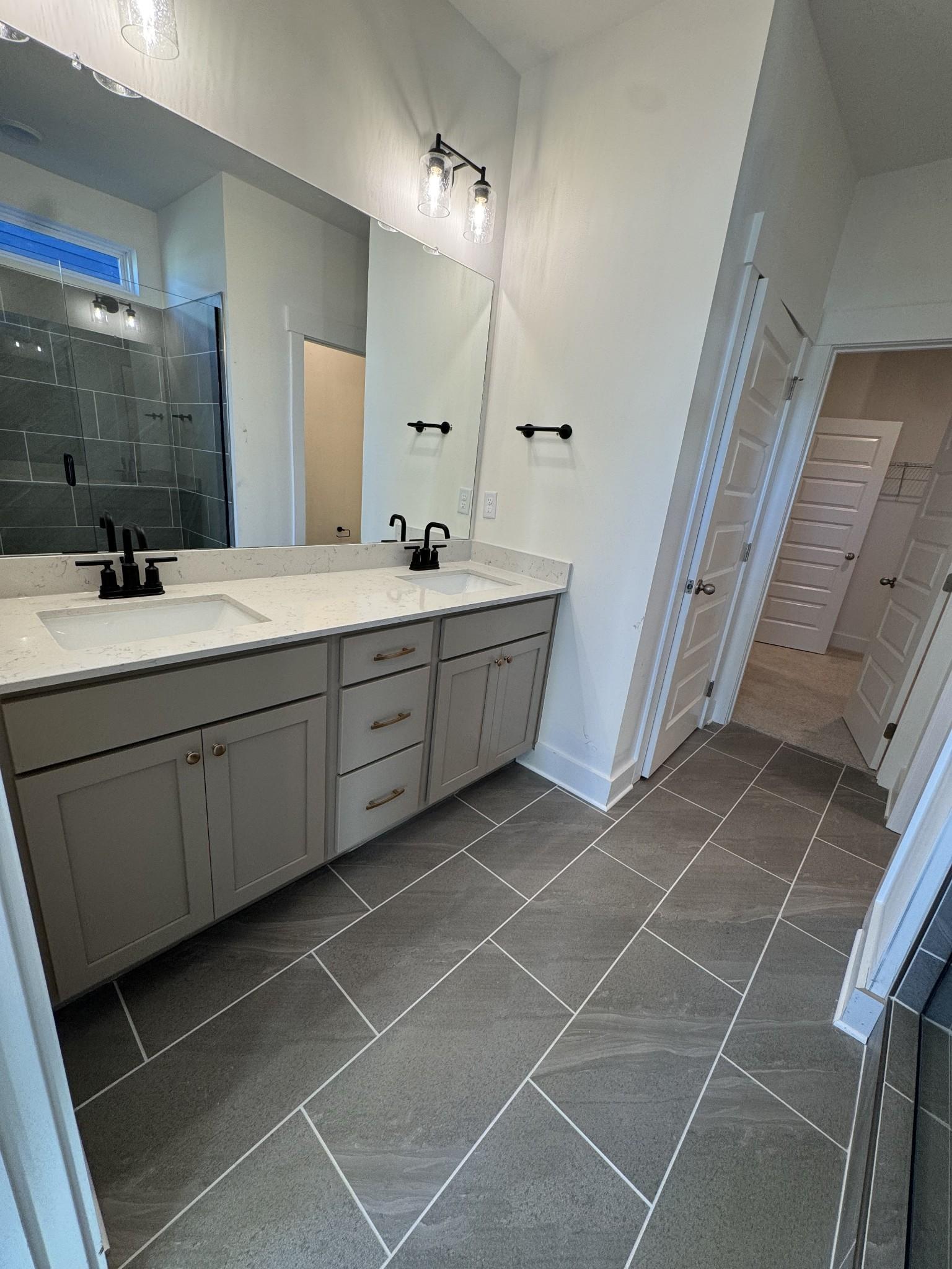 Elegant master bathroom with double vanity, quartz counters, frameless glass shower in Davidson Homes The Ash A, Gallatin, TN