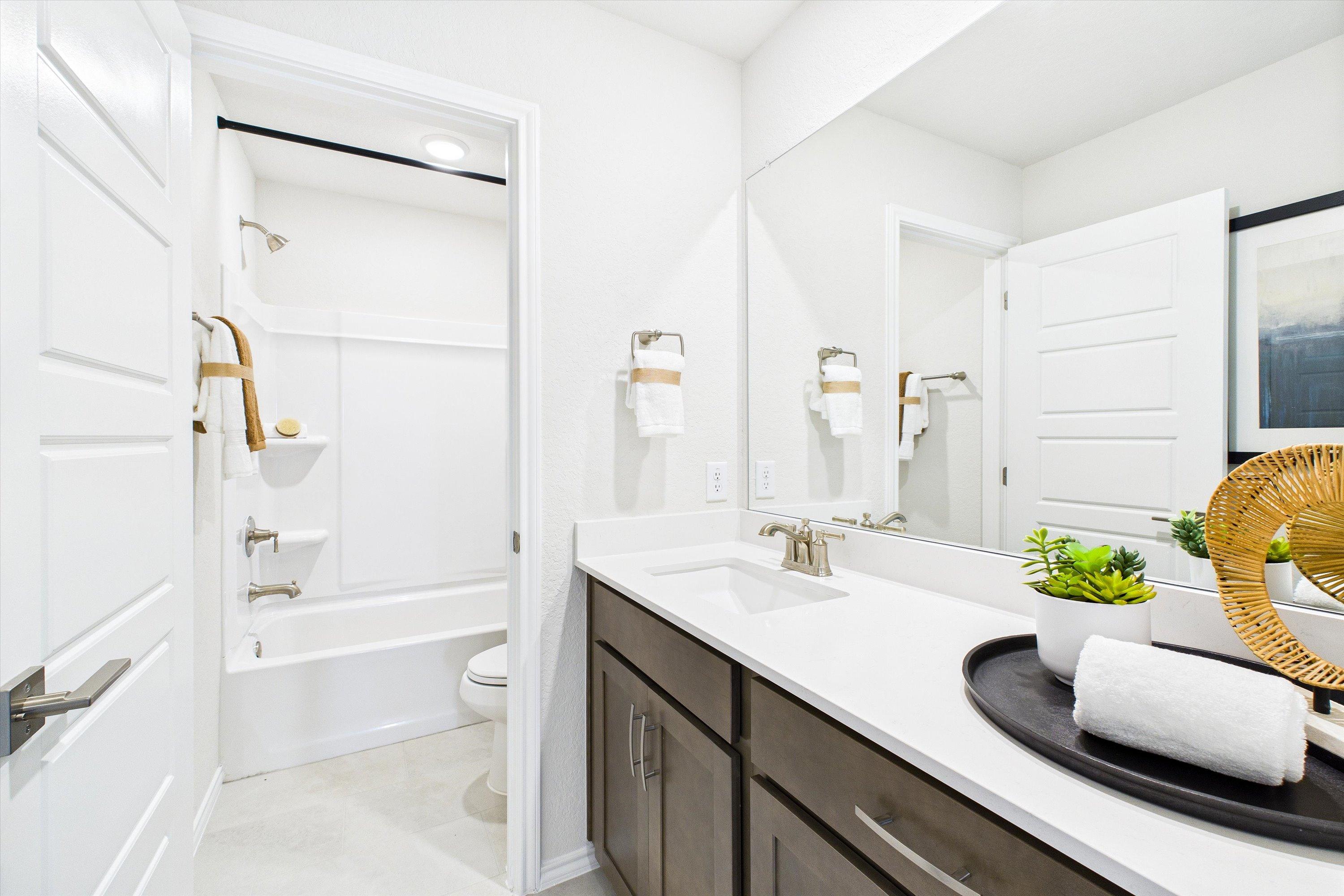 Spacious bathroom at Agave in San Antonio TX with white subway tile shower, freestanding tub, dark wood vanity and large mirror