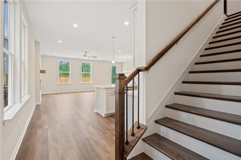 Spacious open foyer with wooden staircase, kitchen island, and large windows in Davidson Homes The Cary B, Kennesaw, GA