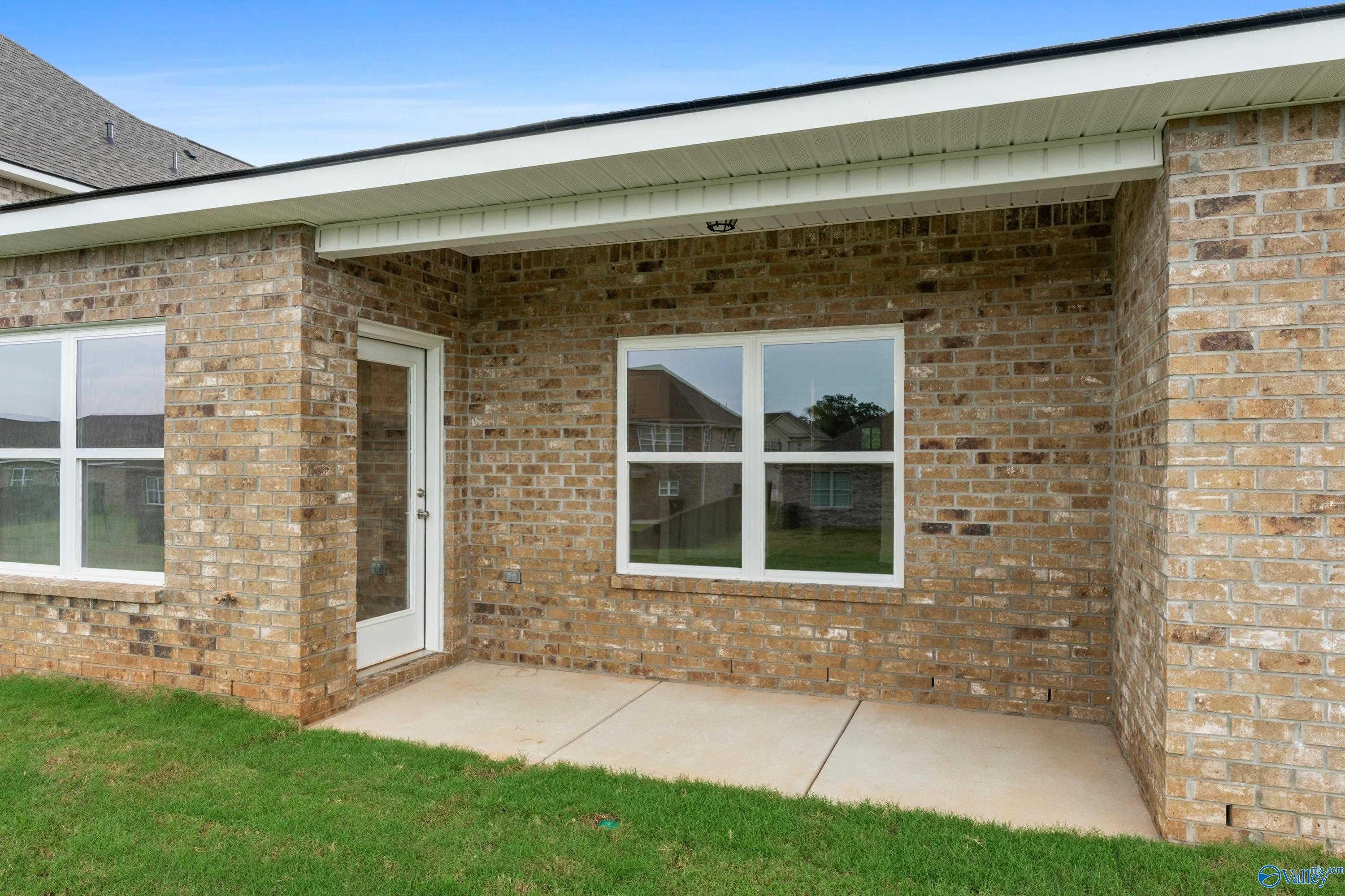 Brick exterior of Davidson Homes The Asheville C with covered patio, large windows, and glass door in Creek Grove, New Market, Alabama