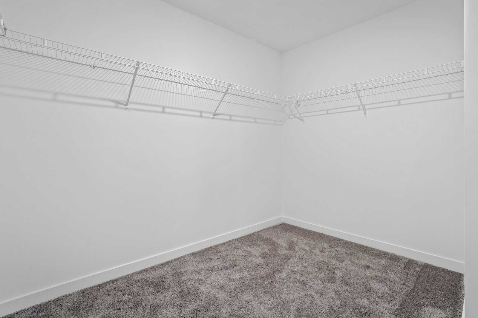 Spacious walk-in closet with wire shelving, white walls, and gray carpet in Davidson Homes The Logan B, Calista Farms
