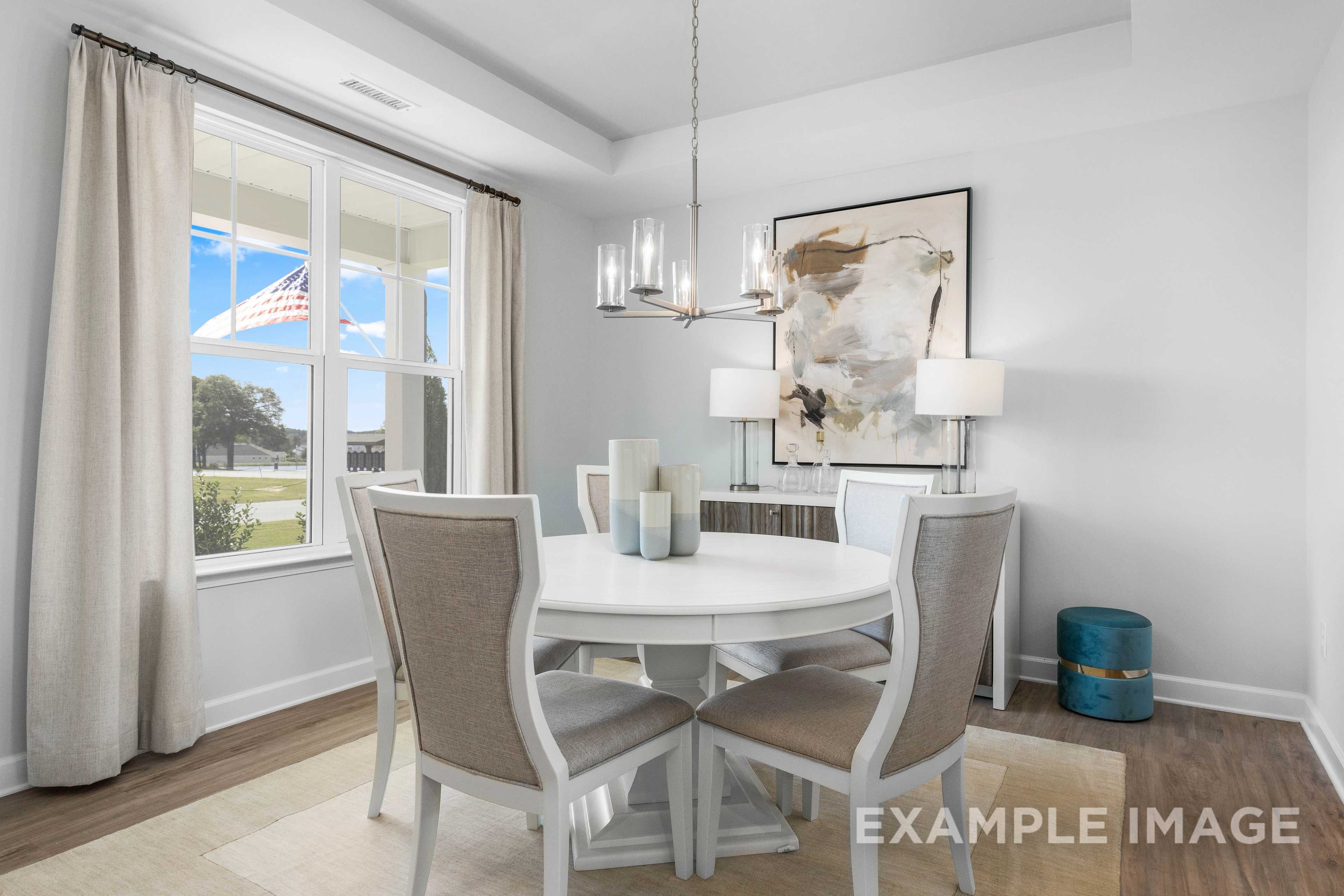 Spacious dining room in The Ash C by Davidson Homes featuring round white table, upholstered chairs, chandelier, and large windows with scenic view