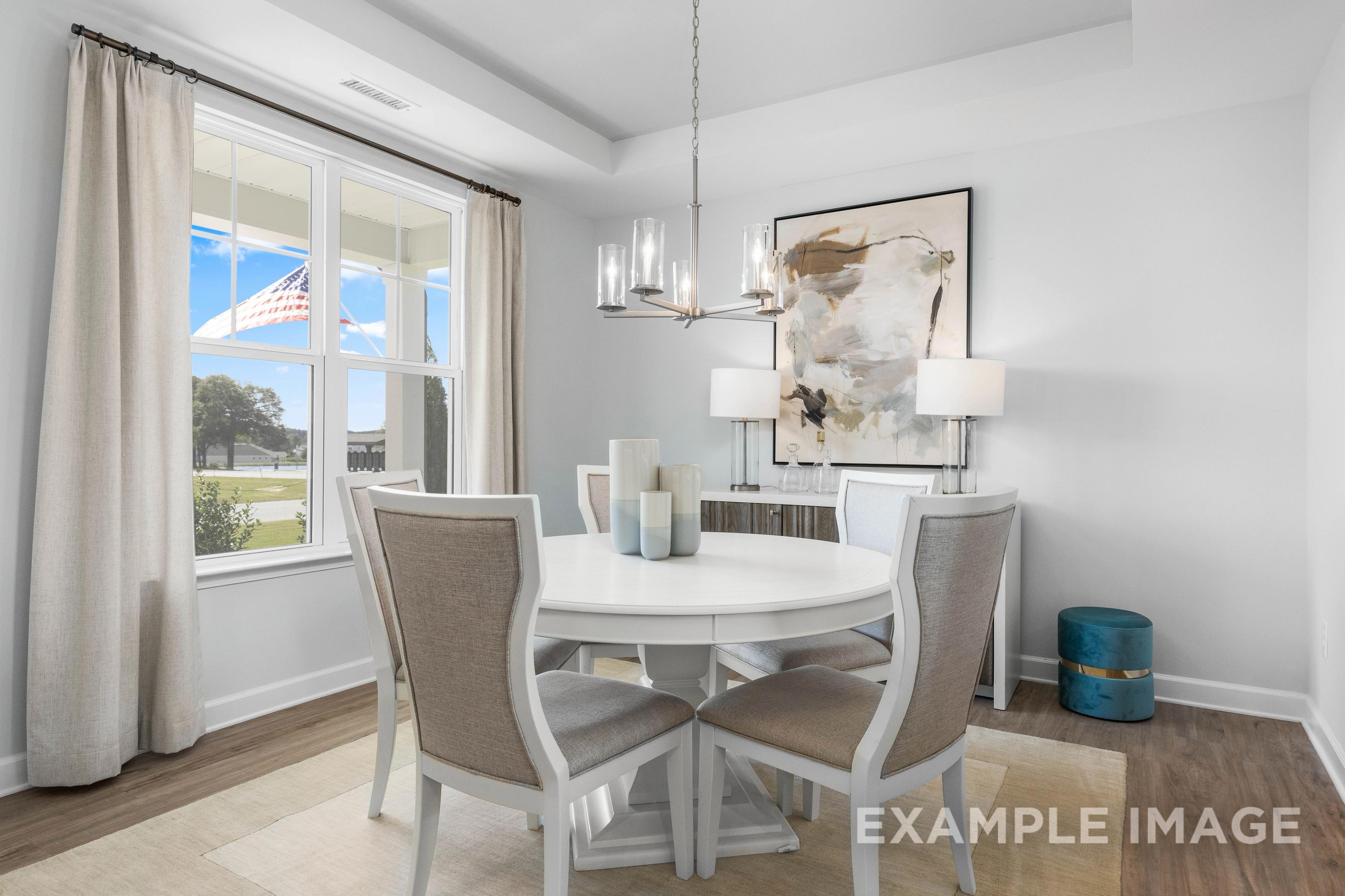 Spacious dining room in The Ash C by Davidson Homes featuring round white table, upholstered chairs, chandelier, and large windows with scenic view