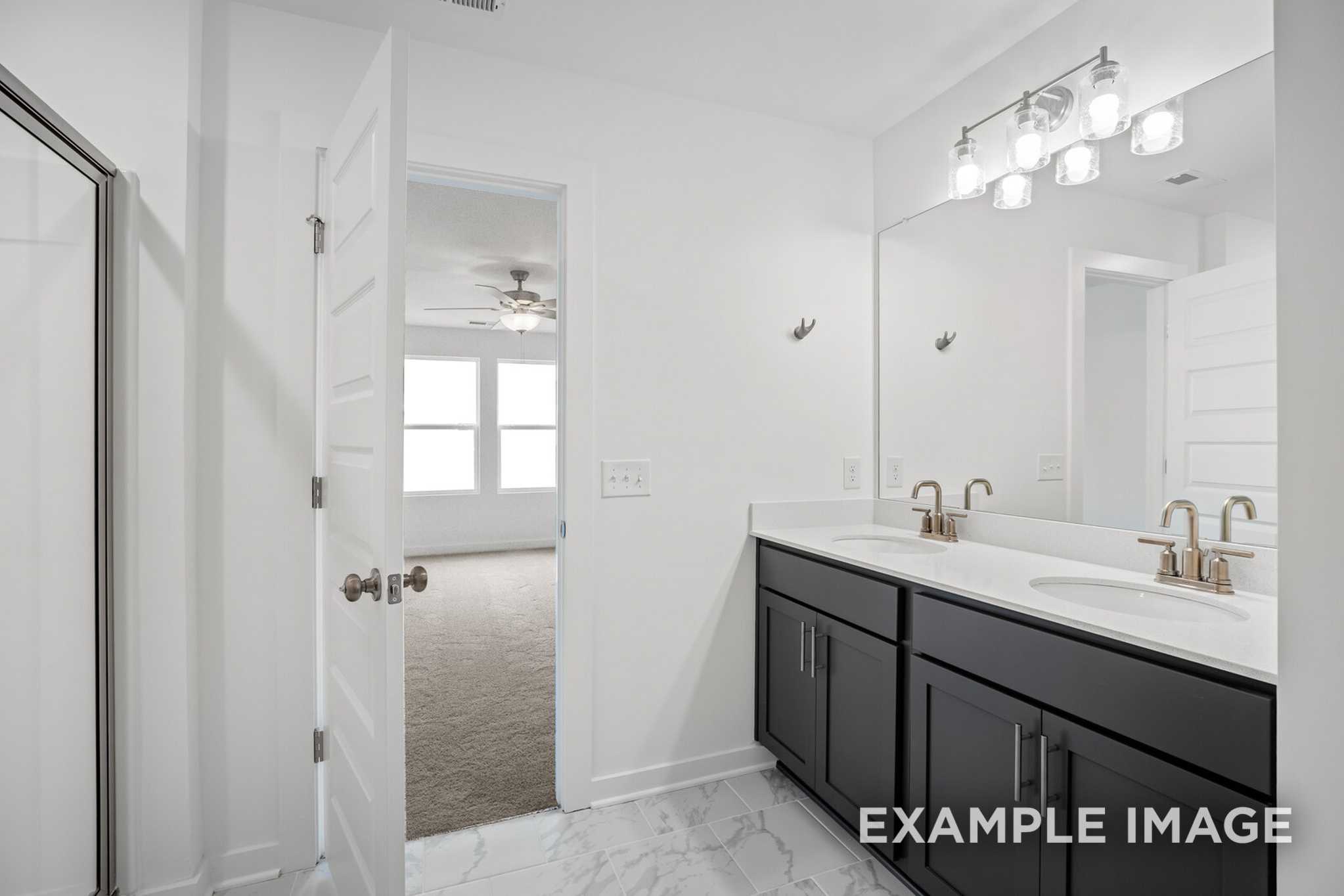 Spacious master bathroom in The Murray B with dual black cabinet vanities, white quartz counters, walk-in shower, and adjacent upper-floor bedroom
