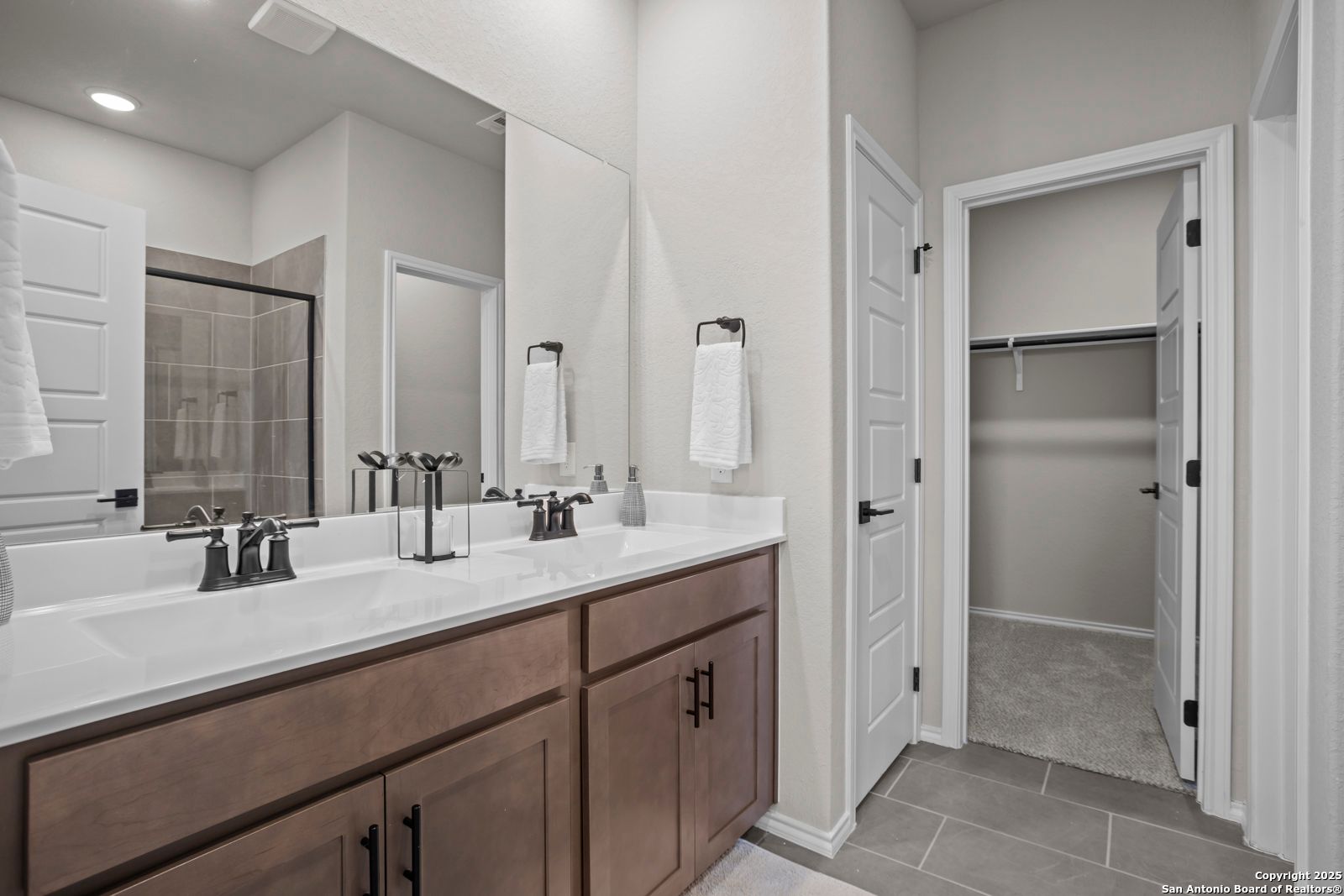 Modern master bathroom with double vanity, walk-in shower, and adjacent closet in Davidson Homes The Asheville H, Converse, TX