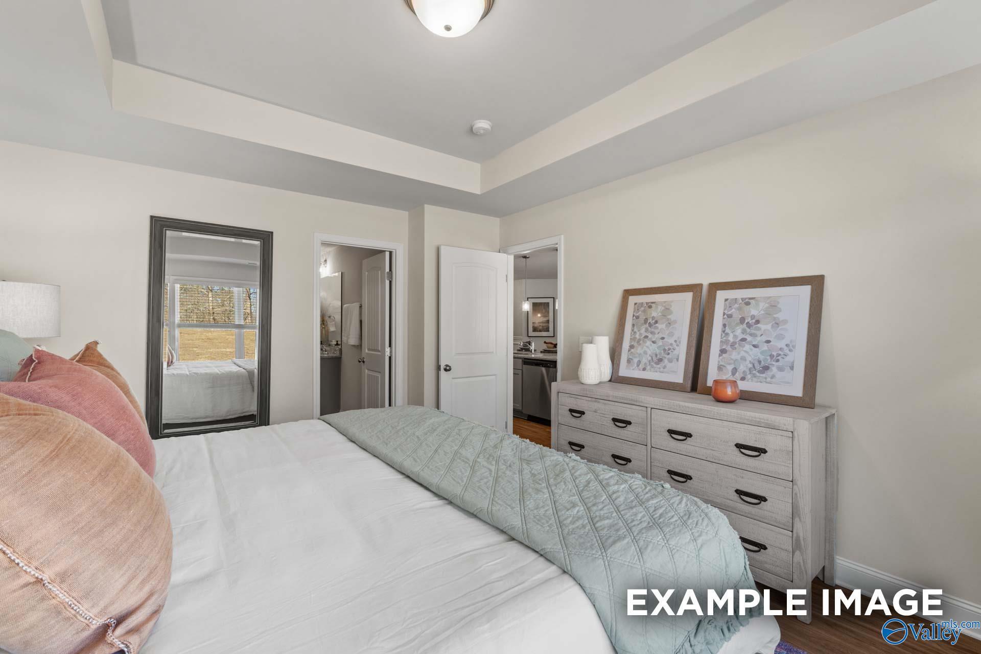 Serene master bedroom with plush bed, teal comforter, dresser, and en-suite bath in Davidson Homes The Franklin C, New Market, Alabama