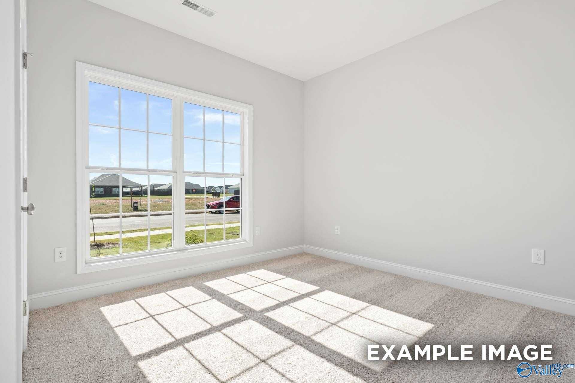 Bright empty bedroom with large sunny window overlooking green field and homes in The Franklin C, Walker's Hill, Meridianville, Alabama