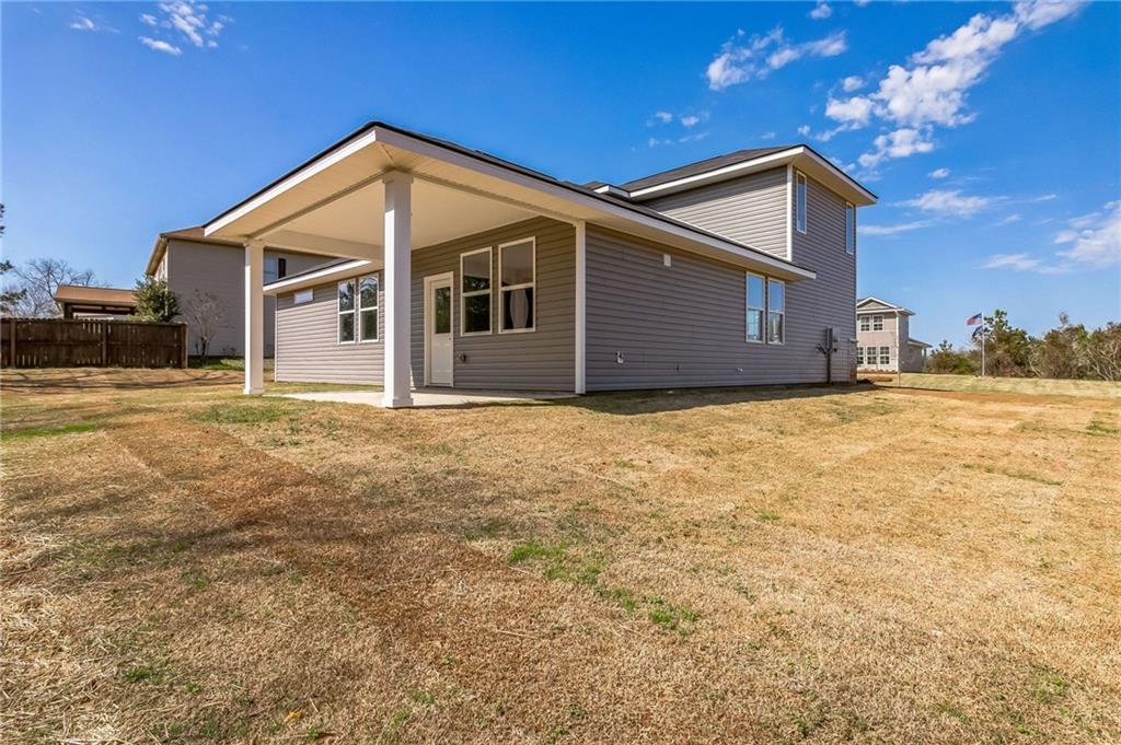 Two-story gray home with covered porch, two-car garage, and dry grassy yard in Ivy Glen, Perry, Georgia by Evermore Homes The Stella