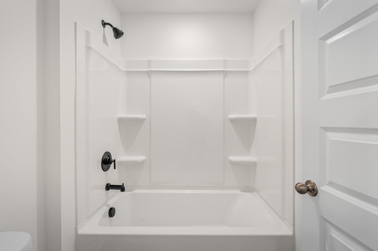 Bright white bathroom with tub-shower combo, black fixtures, and built-in shelves in Davidson Homes The Ash A, Gallatin, Tennessee
