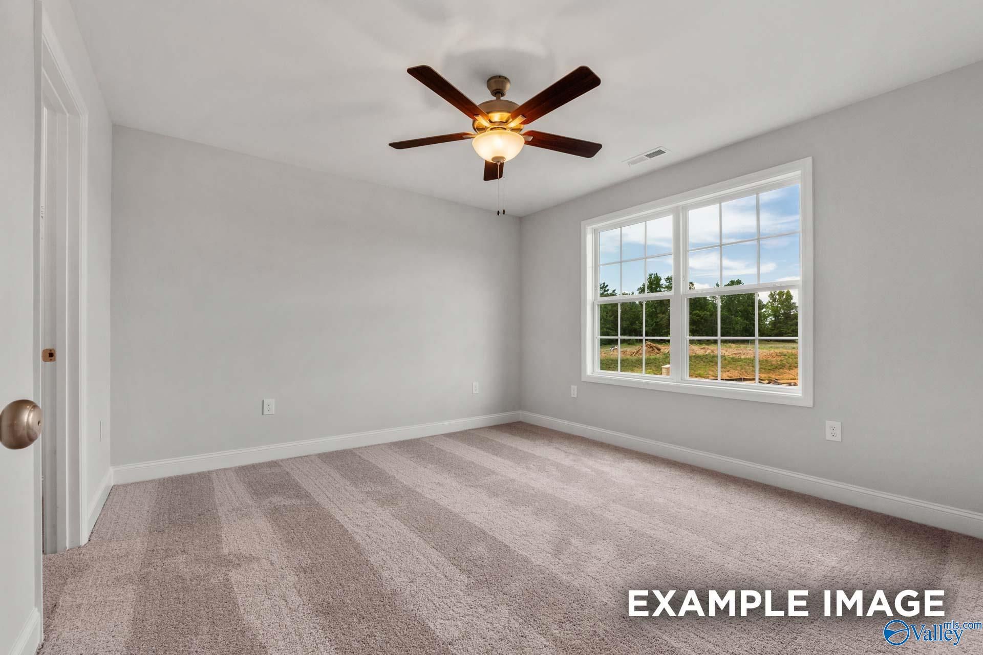 Bright bedroom with gray walls, ceiling fan, and large window overlooking trees in The Shelby C 4-bedroom home, Arab, Alabama