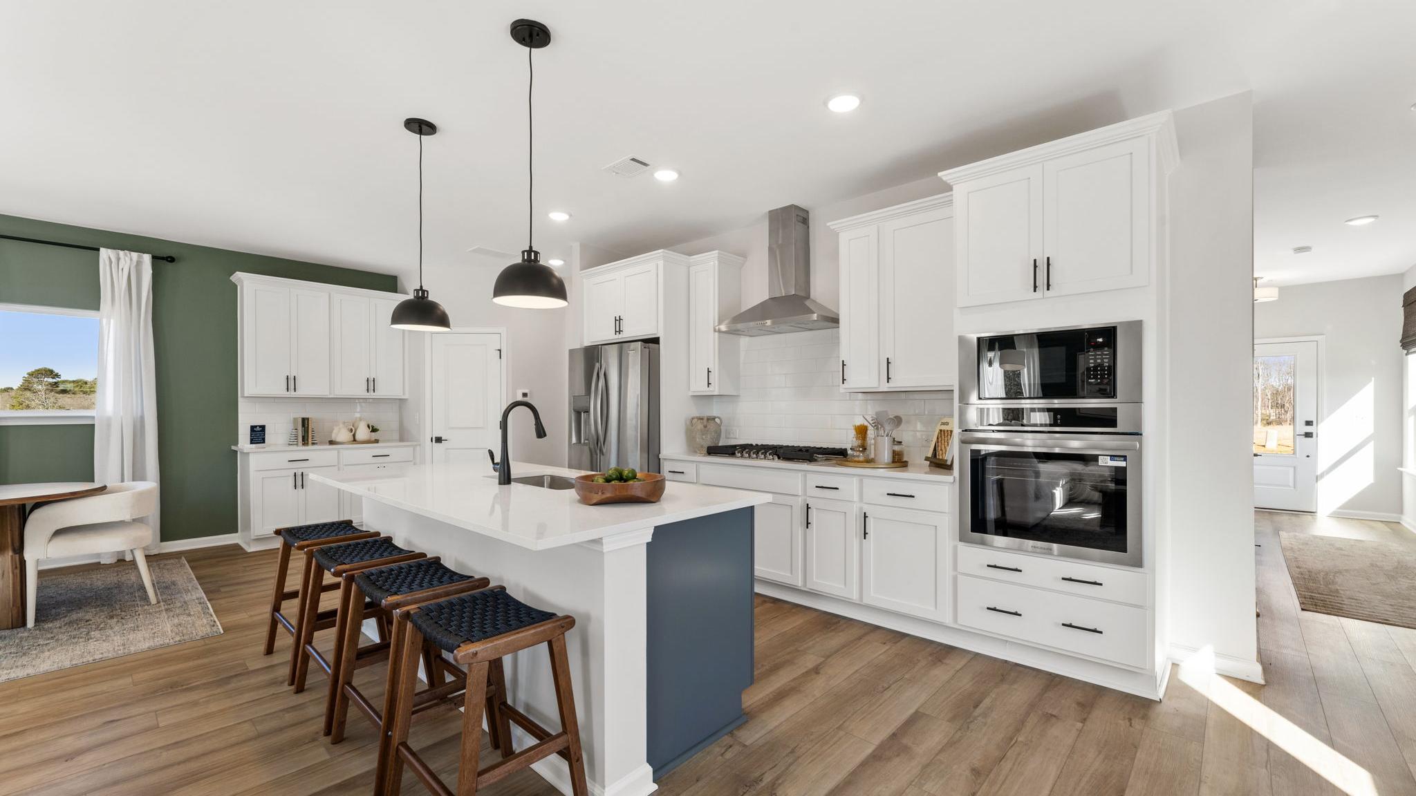 Spacious modern kitchen in Cedar Farms Winder GA with white shaker cabinets, dark quartz island, gas cooktop, and hardwood floors