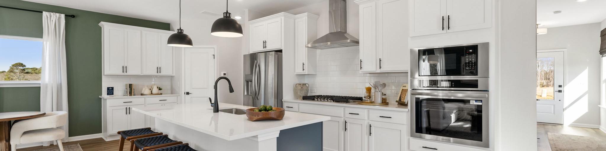 Spacious modern kitchen in Cedar Farms Winder GA with white shaker cabinets, dark quartz island, gas cooktop, and hardwood floors