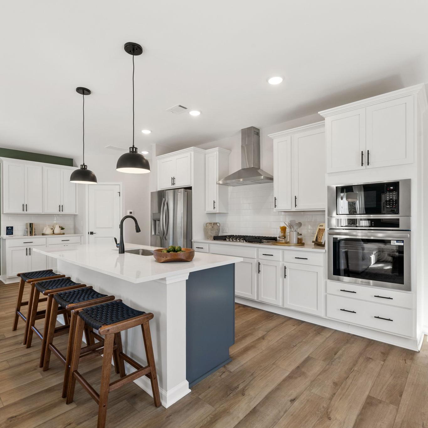 Spacious modern kitchen in Cedar Farms Winder GA with white shaker cabinets, dark quartz island, gas cooktop, and hardwood floors