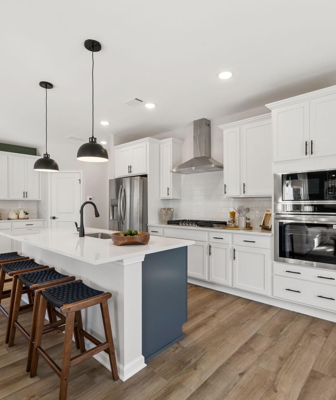 Spacious modern kitchen in Cedar Farms Winder GA with white shaker cabinets, dark quartz island, gas cooktop, and hardwood floors