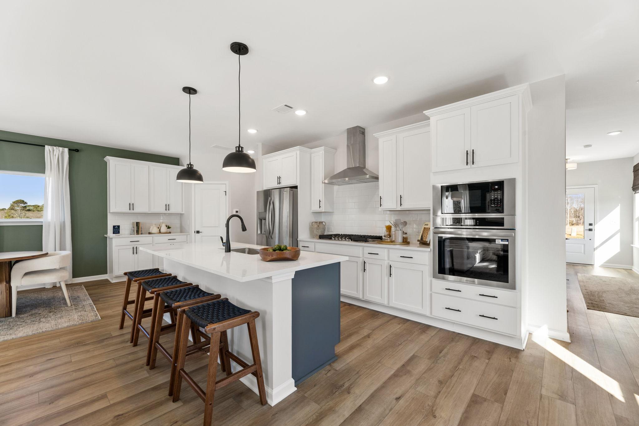 Spacious modern kitchen in Cedar Farms Winder GA with white shaker cabinets, dark quartz island, gas cooktop, and hardwood floors