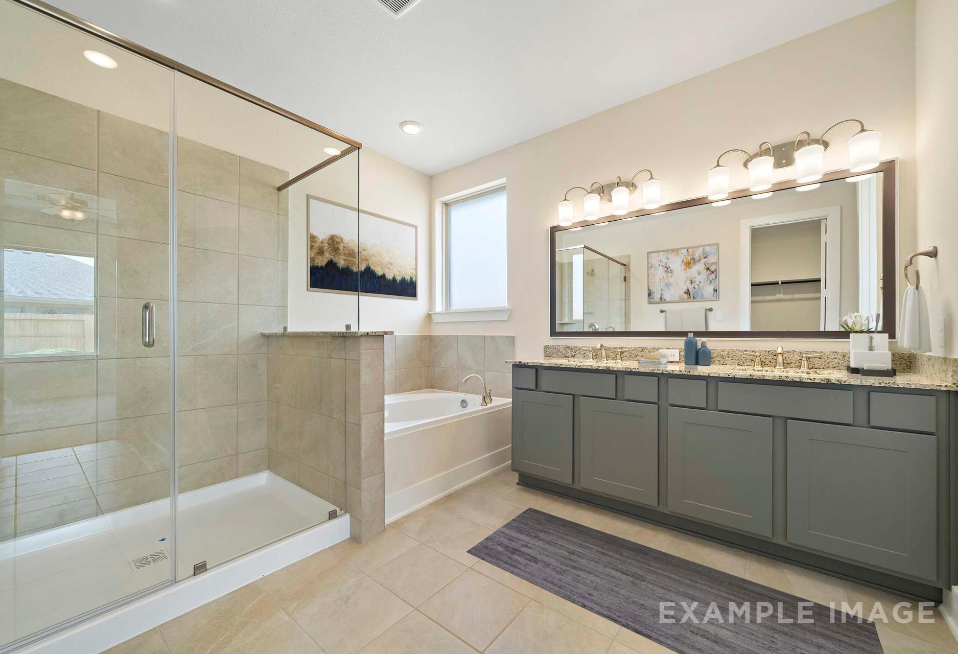 Spacious master bathroom in The Diana A with glass shower, soaking tub, double vanity, and neutral tiles
