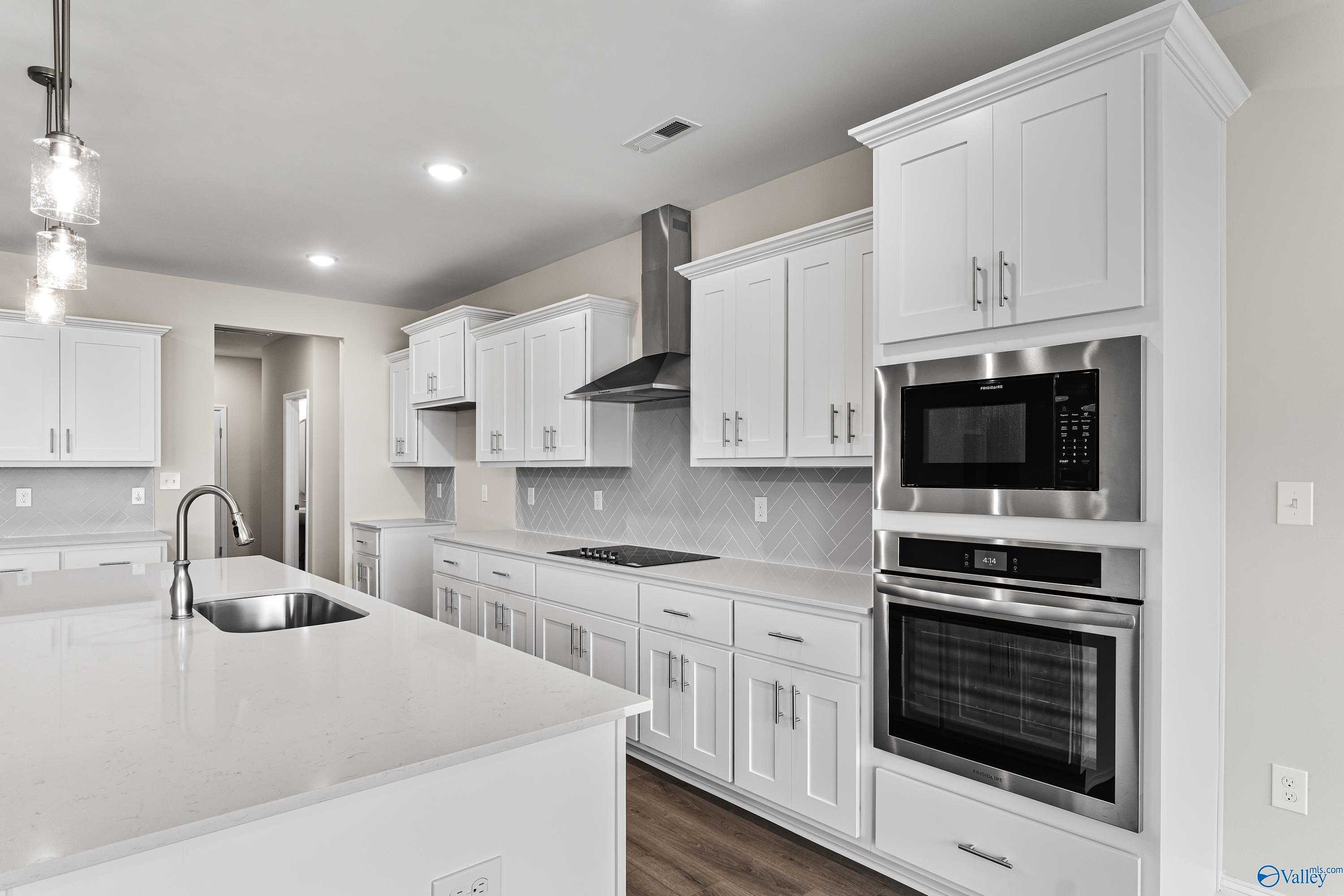 Modern white shaker kitchen with quartz island, stainless double oven, subway tile backsplash in The Finleigh, Toney, Alabama