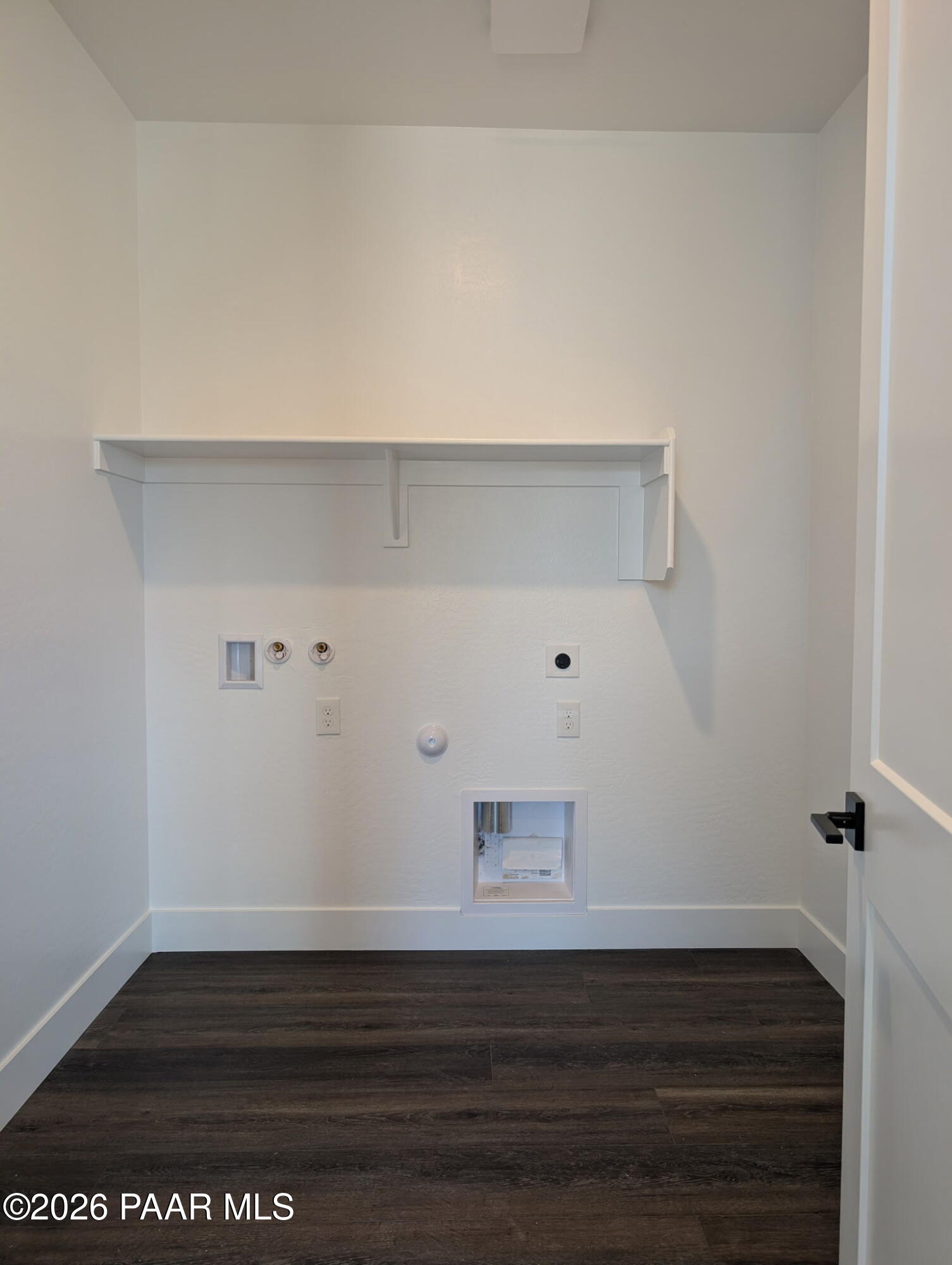 Laundry room with utility hookups and storage shelf in The Frontier II F floor plan by Davidson Homes in Prescott, AZ.