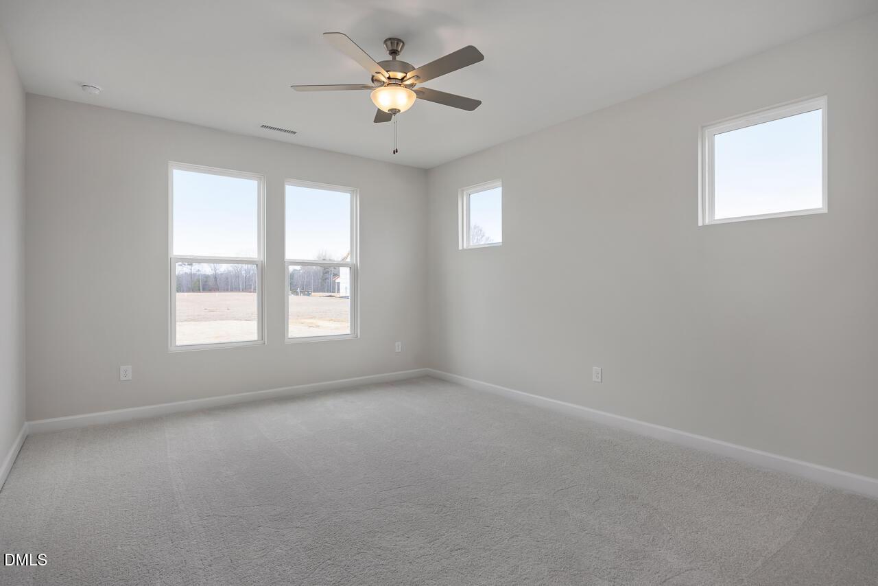 Bright secondary bedroom with large windows, ceiling fan, and neutral walls in The Daphne C by Davidson Homes, Lillington, NC