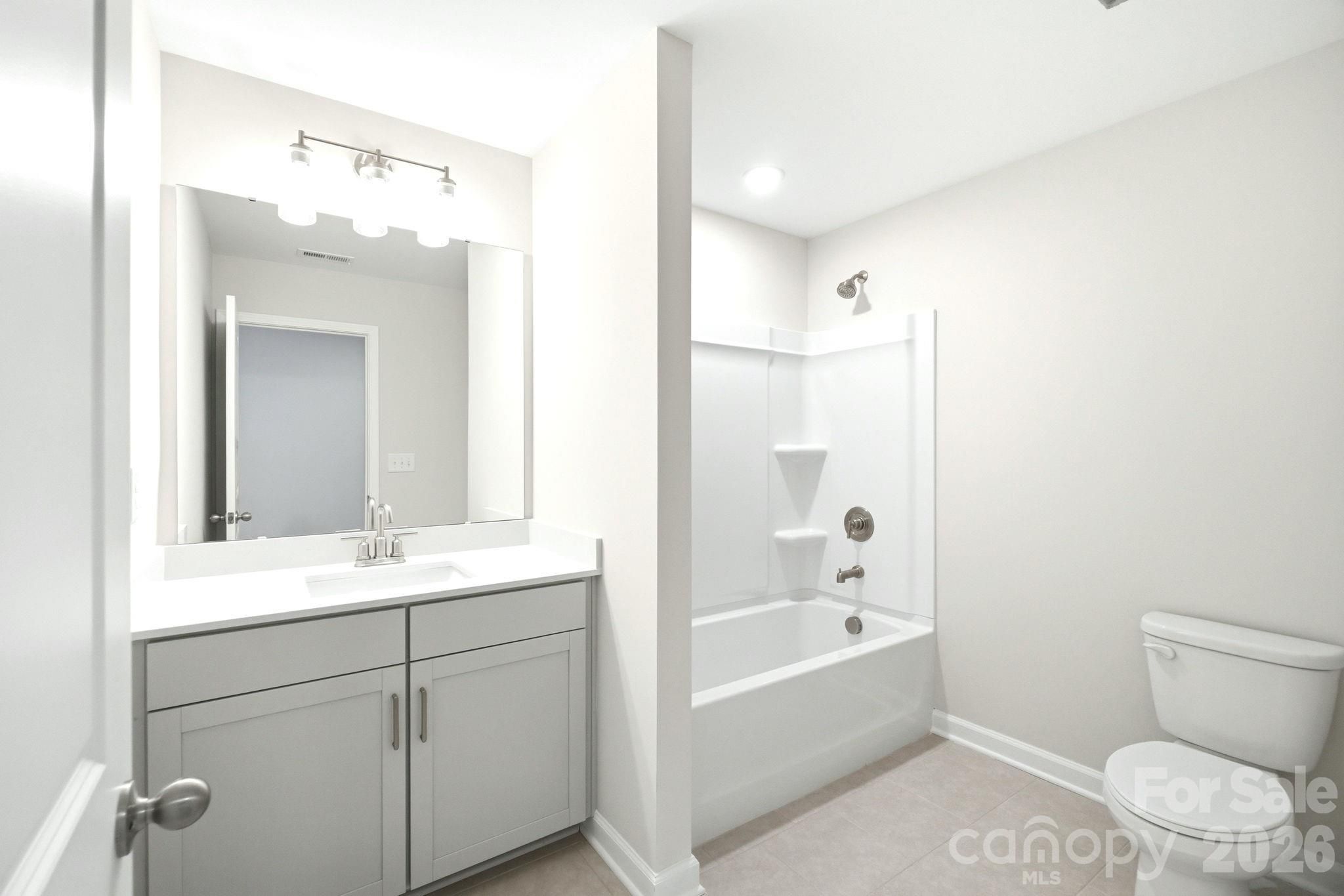 Modern bathroom with gray vanity, white countertop, and tub-shower combo in Davidson Homes' The Magnolia B plan, Mooresville.