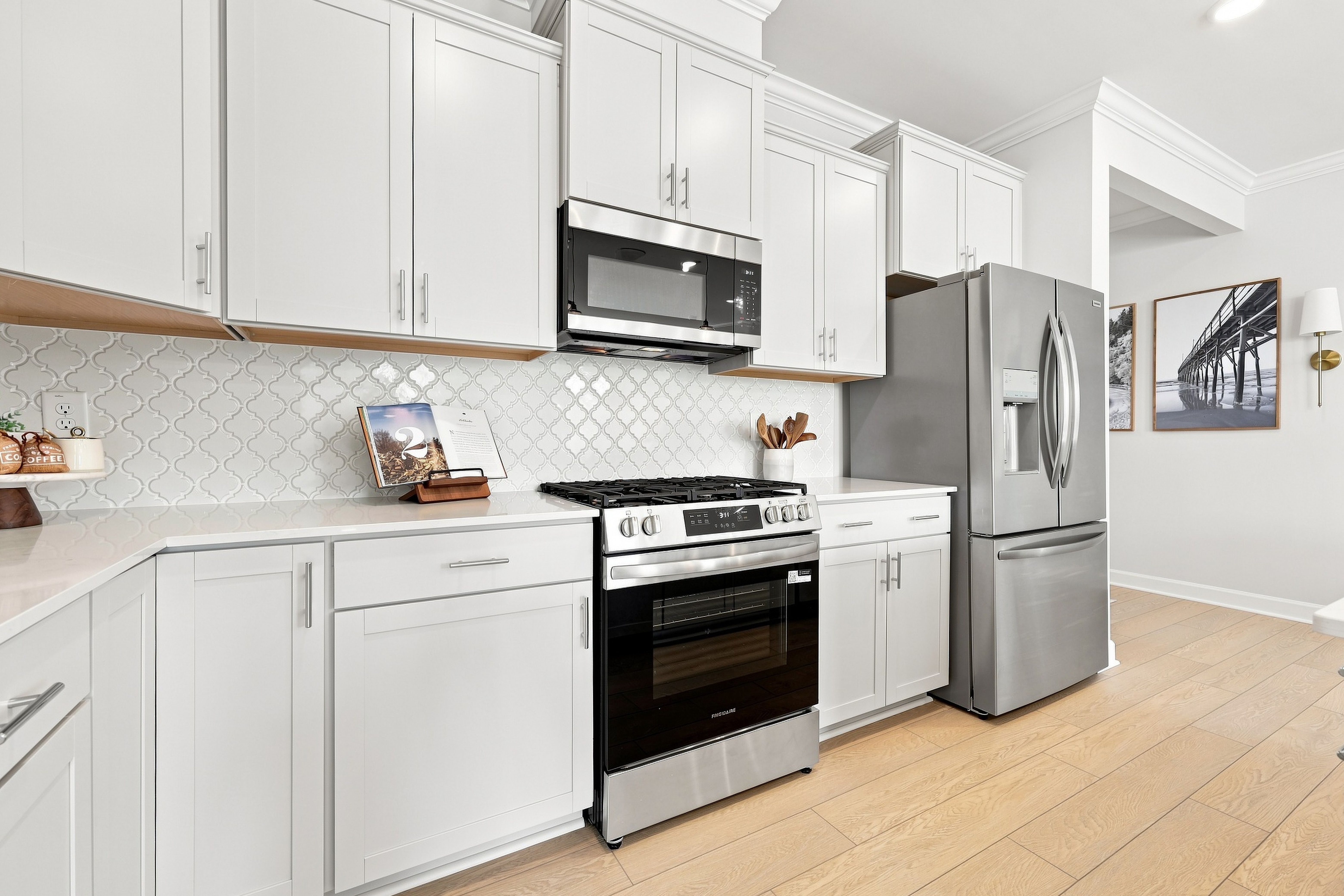 Modern kitchen in The Daphne D featuring white shaker cabinets, quartz countertops, and stainless steel appliances.