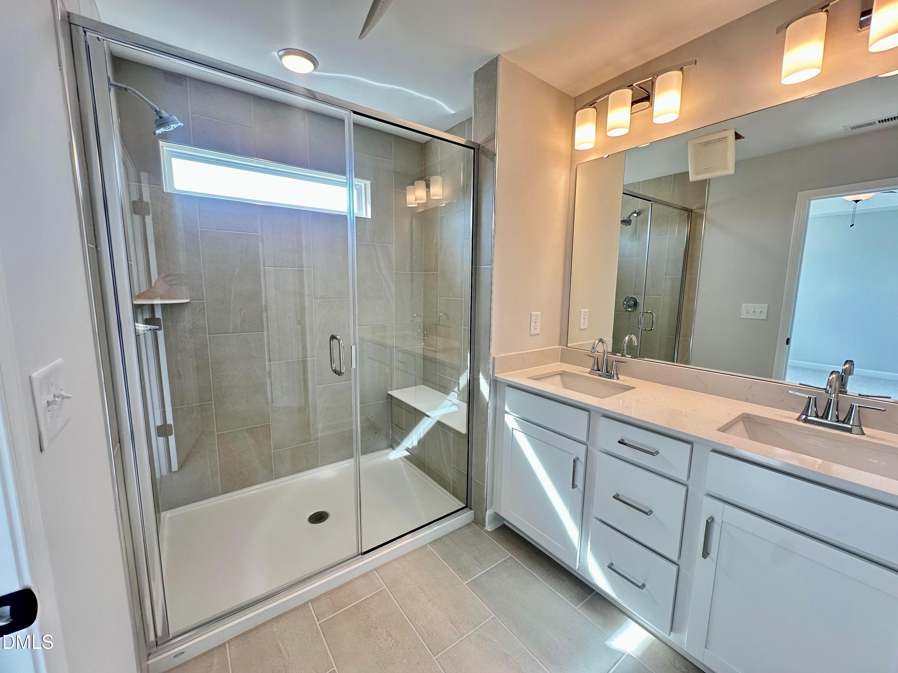 Luxurious master bathroom with frameless glass shower, built-in bench, quartz double vanity in Davidson Homes The Avery, Knightdale, NC