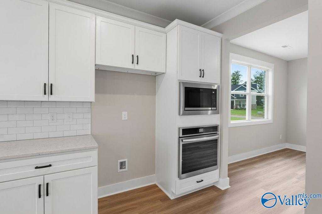 Modern kitchen with white shaker cabinets, subway tile backsplash, stainless double oven in Evermore Homes The Oxford, Owens Cross Roads, AL