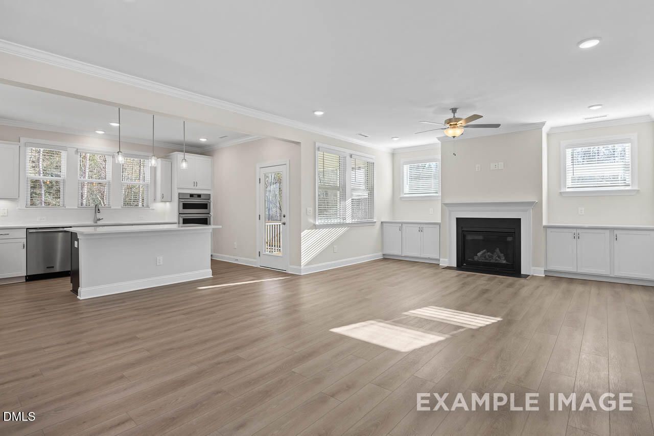 Open-concept kitchen-living area with white cabinets, stainless appliances, gas fireplace, and French doors in Davidson Homes The Aspen C, Apex NC