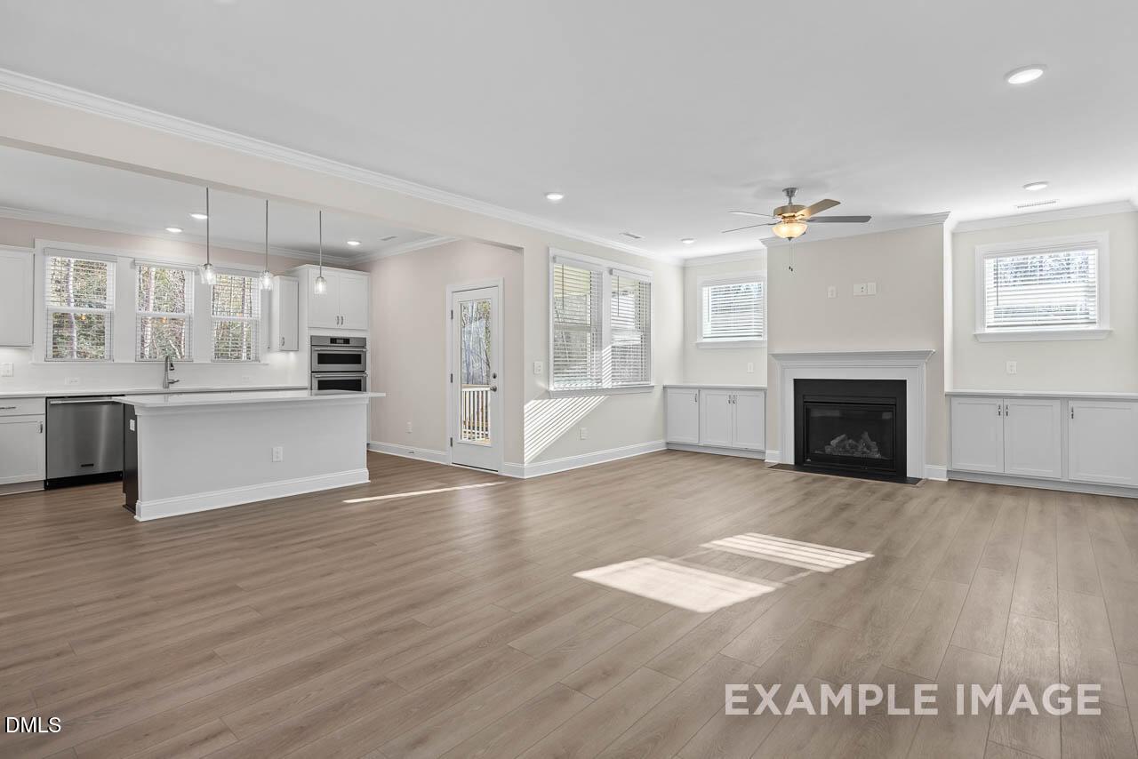 Open-concept living room and gourmet kitchen with gas fireplace in The Aspen C floor plan by Davidson Homes in Apex, NC.