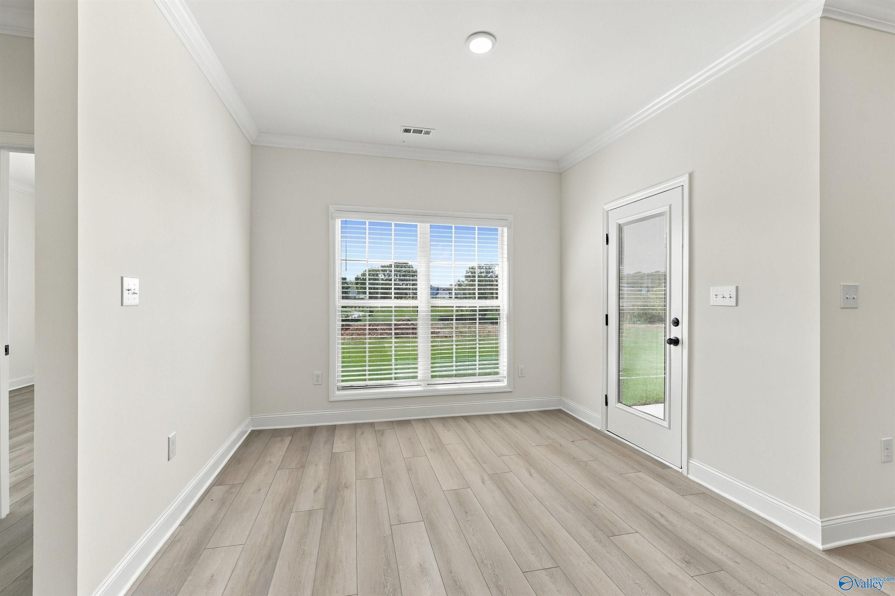 Bright dining room with vinyl plank flooring, garden window, and exterior door in Davidson Homes' The Valencia, Huntsville, Alabama