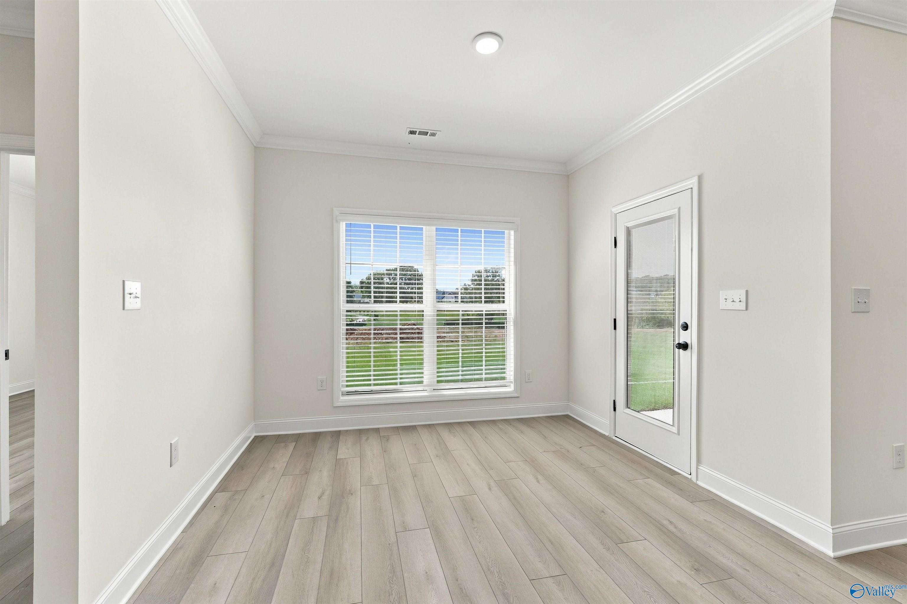 Bright dining room with vinyl plank flooring, garden window, and exterior door in Davidson Homes' The Valencia, Huntsville, Alabama