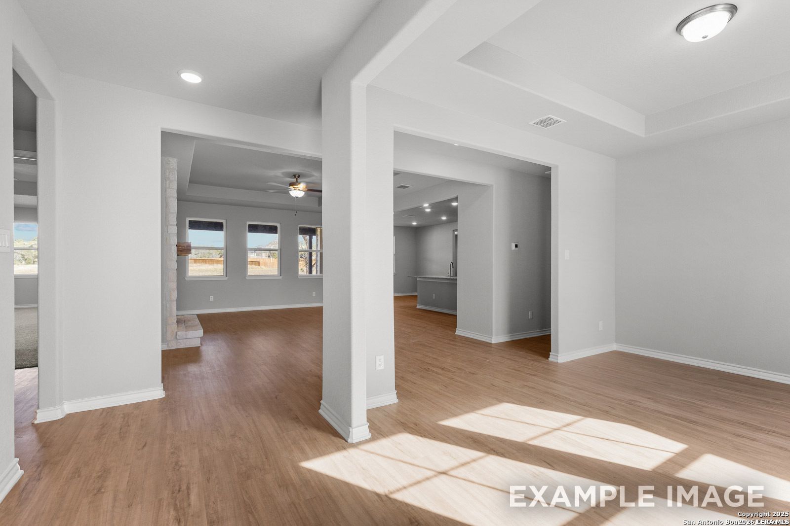 Open-concept living area with wood-style flooring in The Oxford F floor plan by Davidson Homes in Potranco Oaks, Texas.