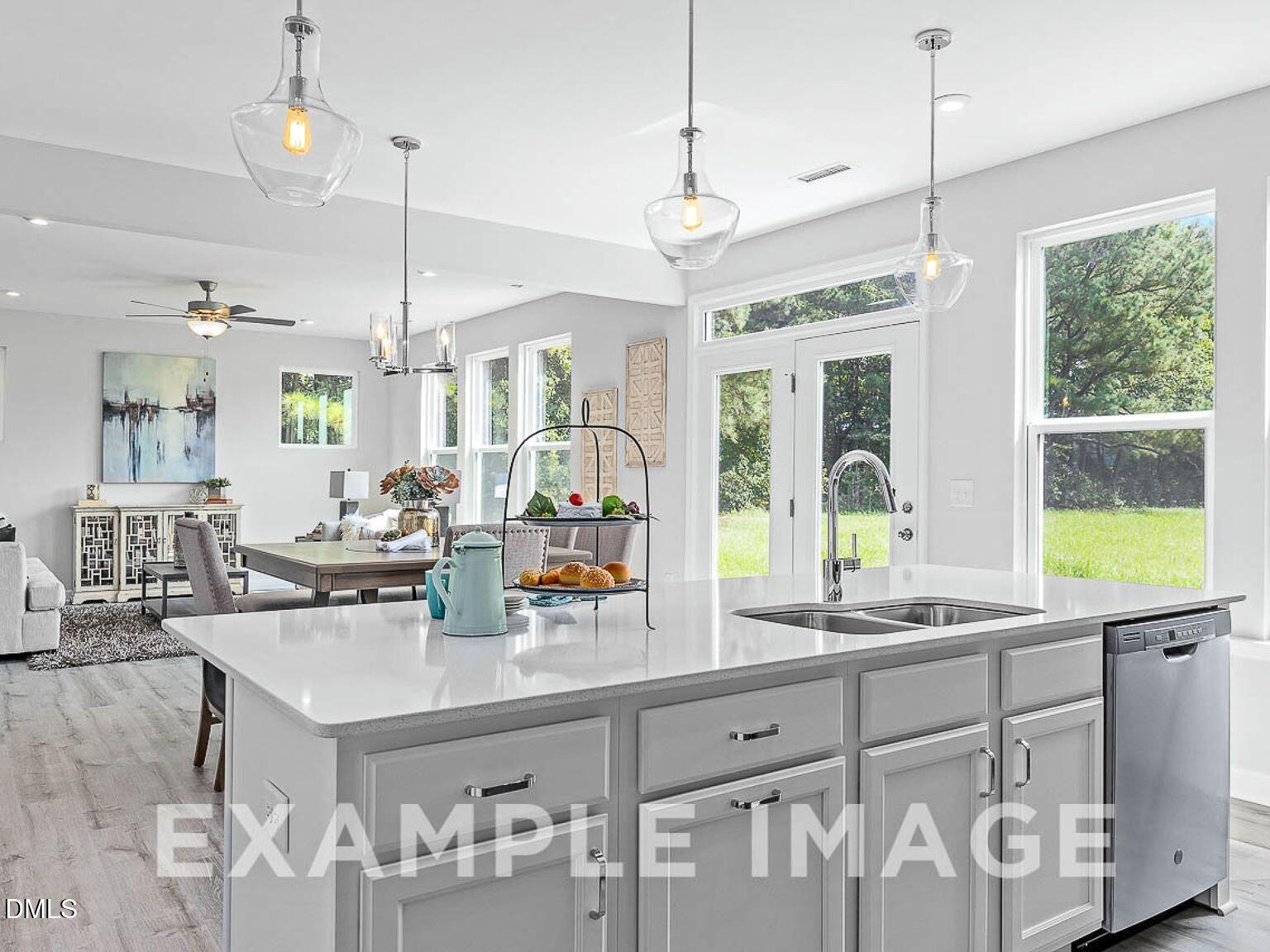 Open-concept kitchen with white island, stainless appliances, and dining nook in Davidson Homes The Chestnut B, Lillington, NC