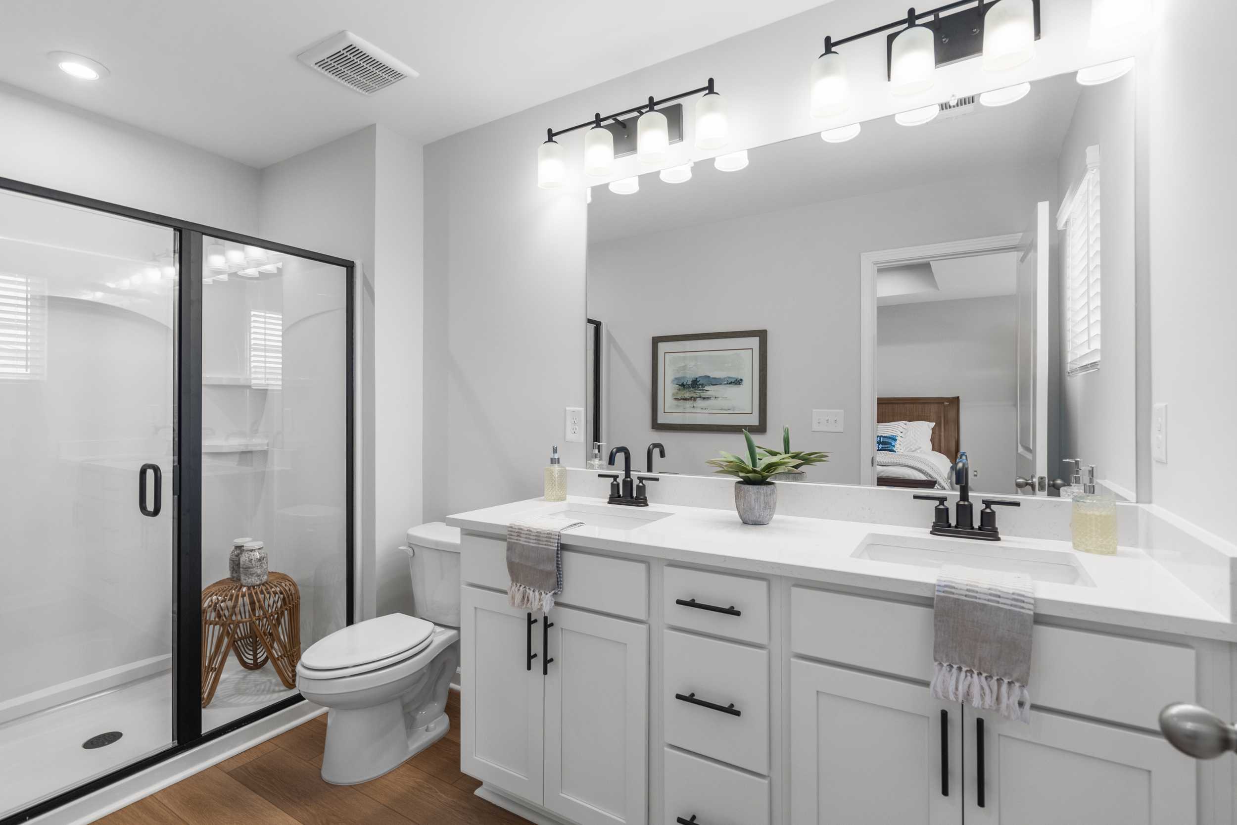 Modern primary bathroom at Stegall Village in Emerson, Georgia with double white vanity, frameless glass shower, and sleek black fixtures