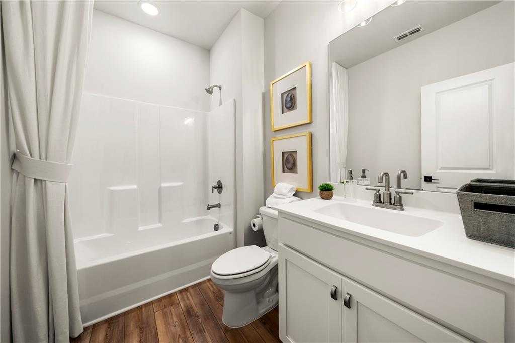 Bright modern bathroom with walk-in shower, soaking tub, vanity, and hardwood floors in Davidson Homes The Hickory B, Riverwood, GA
